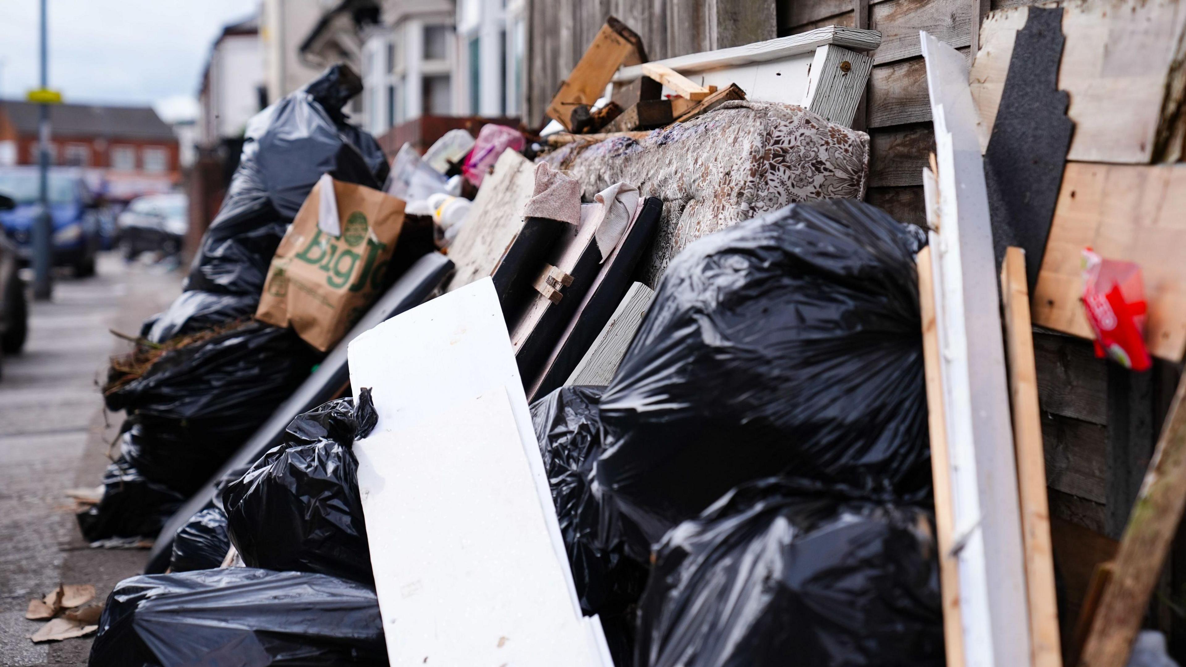 Uncollected bin bags and rubbish in a pile on a street