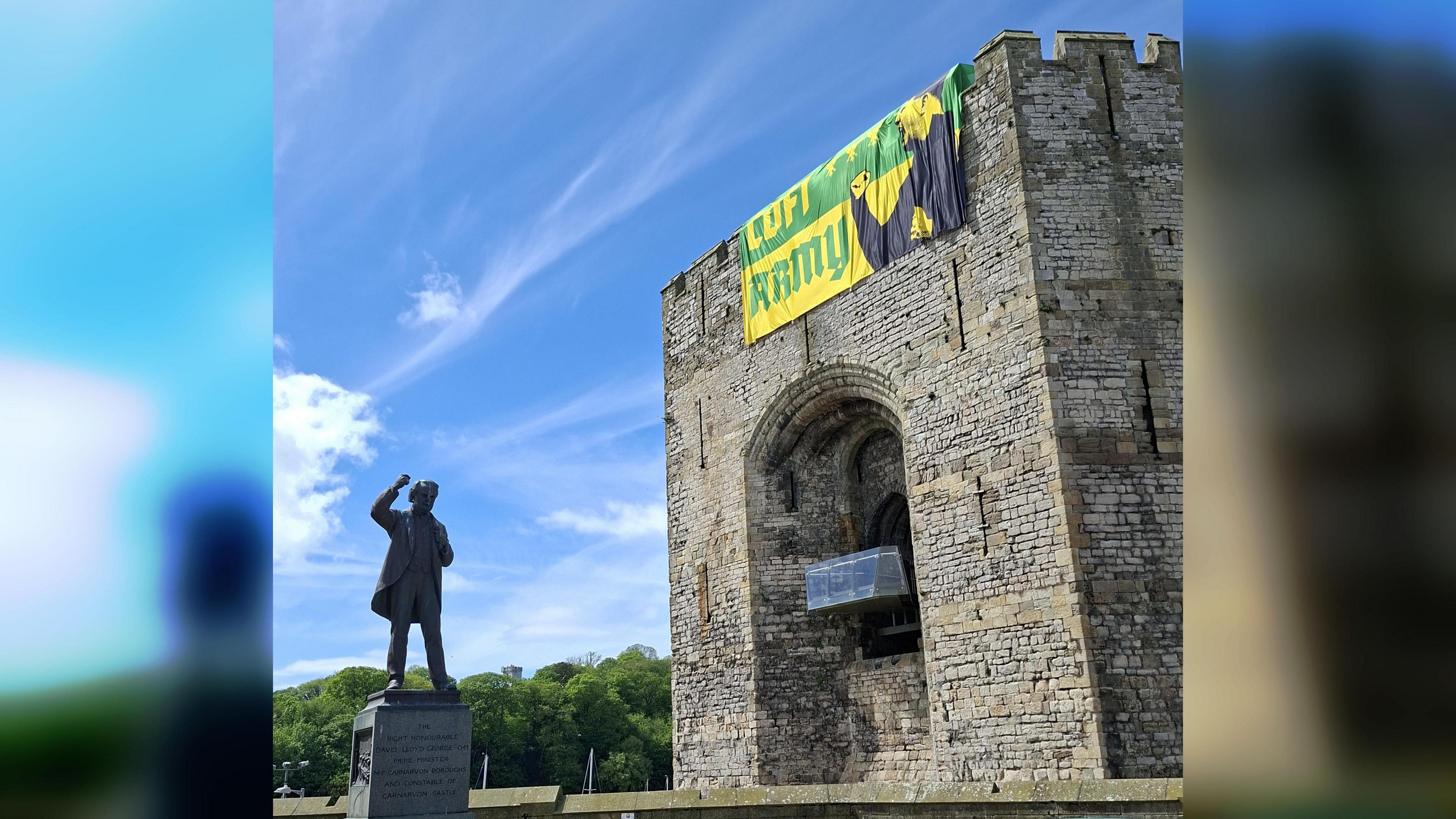 Cerflun Lloyd George o flaen y castell a'r faner Cofi Army