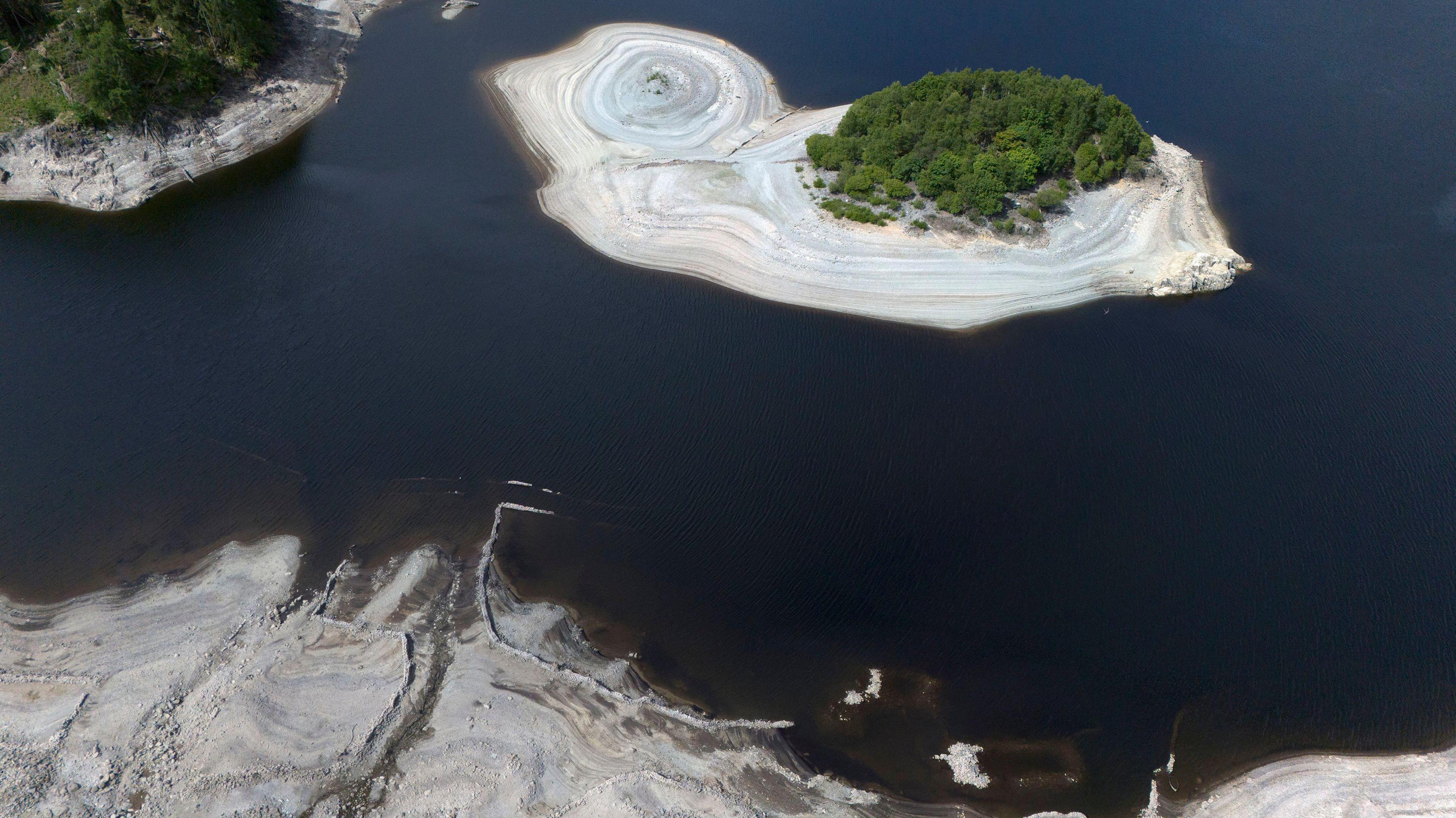 An aerial view of Haweswater reservoir, which shows receding water levels exposing light brown silt-beds.