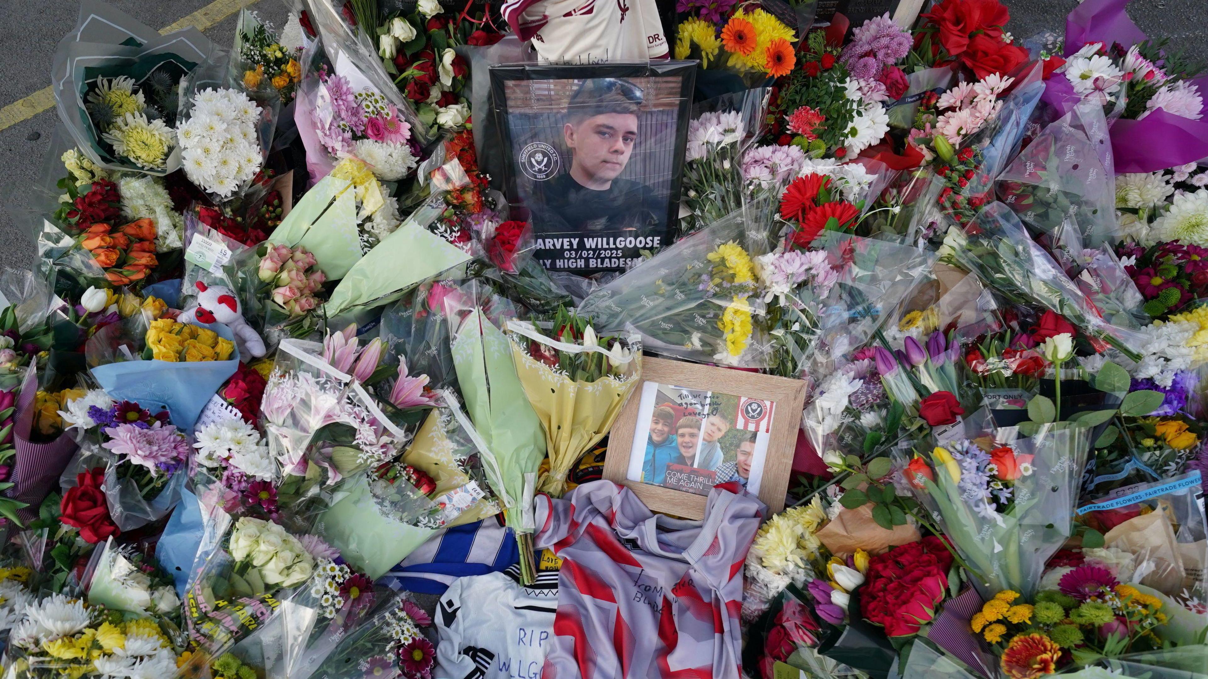 Flowers, frames, letters, and photos form a memorial for Harvey Willgoose.