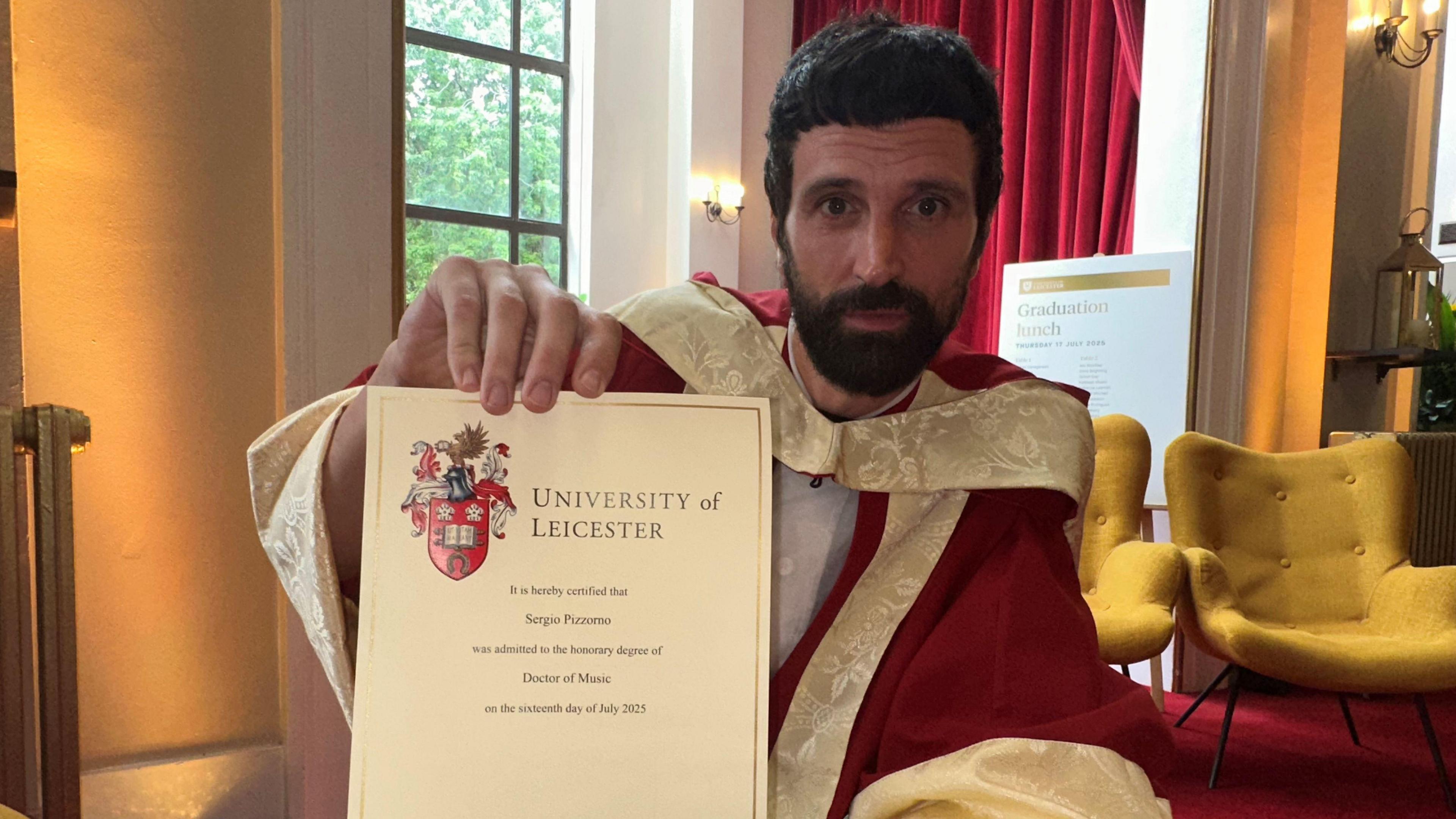 Pizzorno in a red gown holding a graduation certificate
