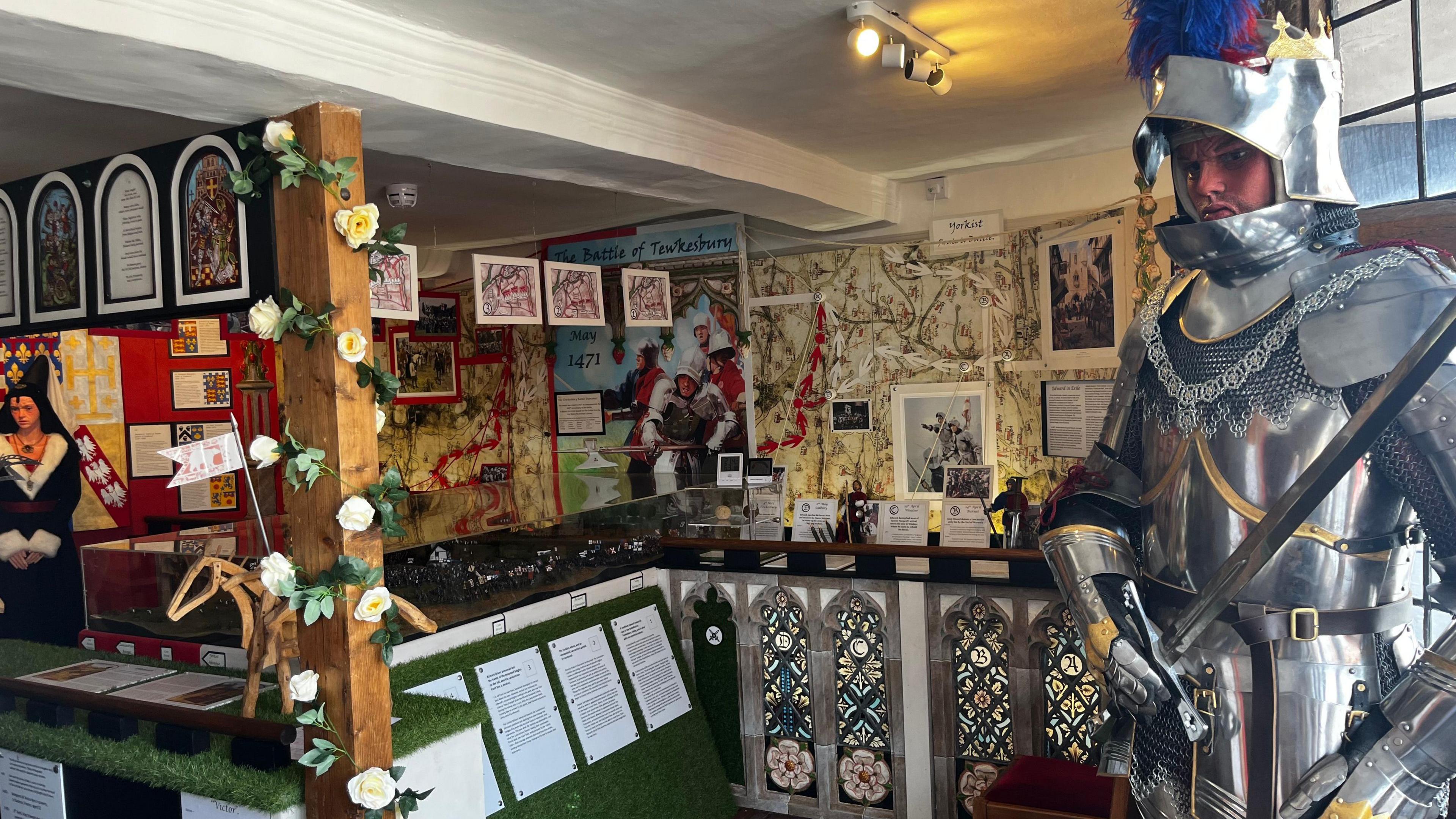 The inside of the museum with a maps and exhibits showing in the background and a mannequin ina  suit of armor to the right in the foreground