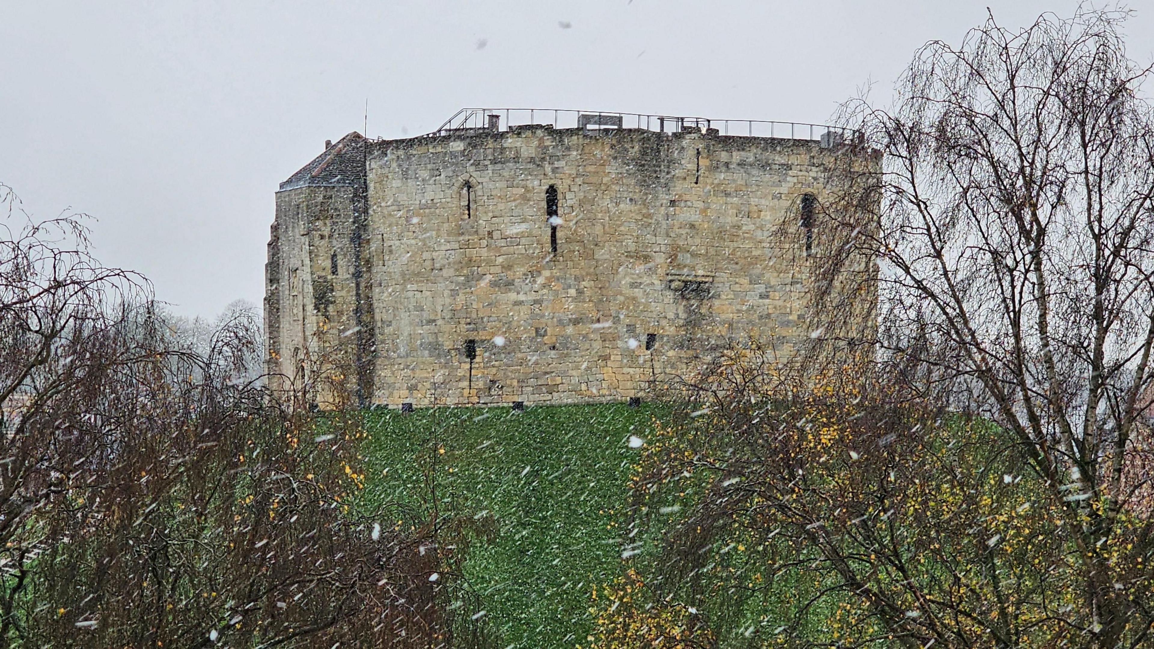 A view of Cliffords Tower in York with snow falling