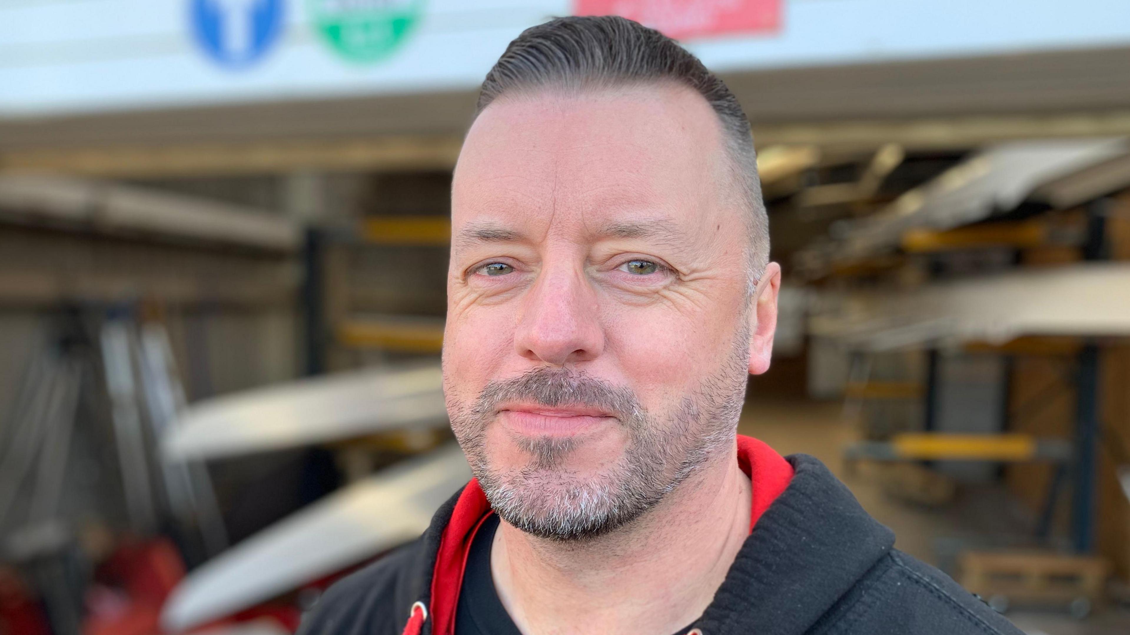Paul Freemantle looking directly into the camera, wearing a black hoodie with red designs on it.
