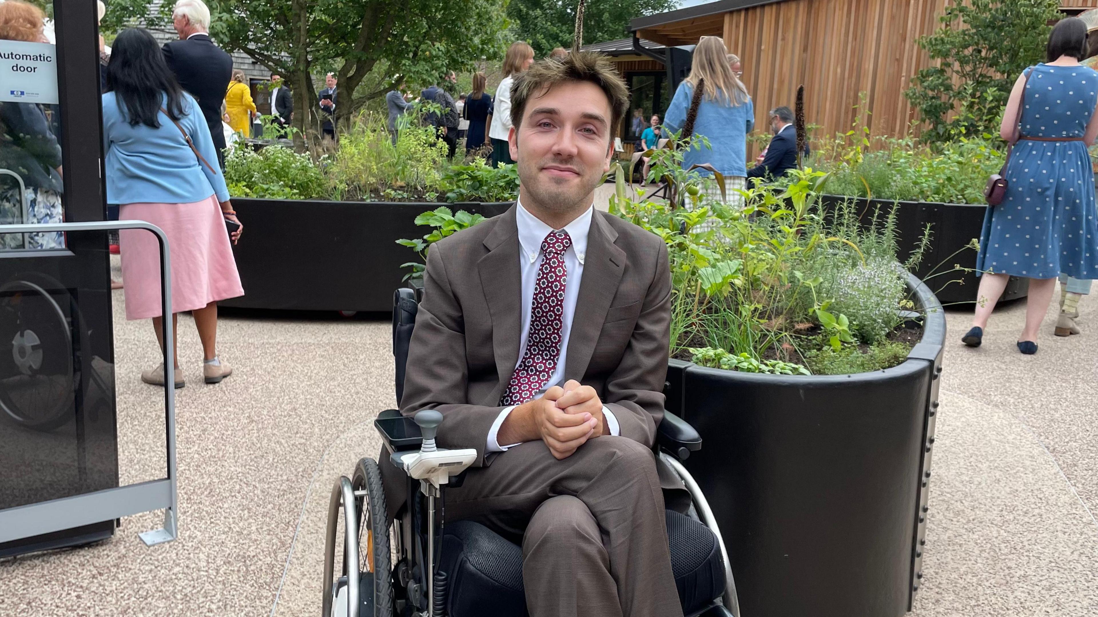 George Robinson, who uses an electric wheelchair, dressed in a brown suit and a patterned tie at the opening ceremony.
