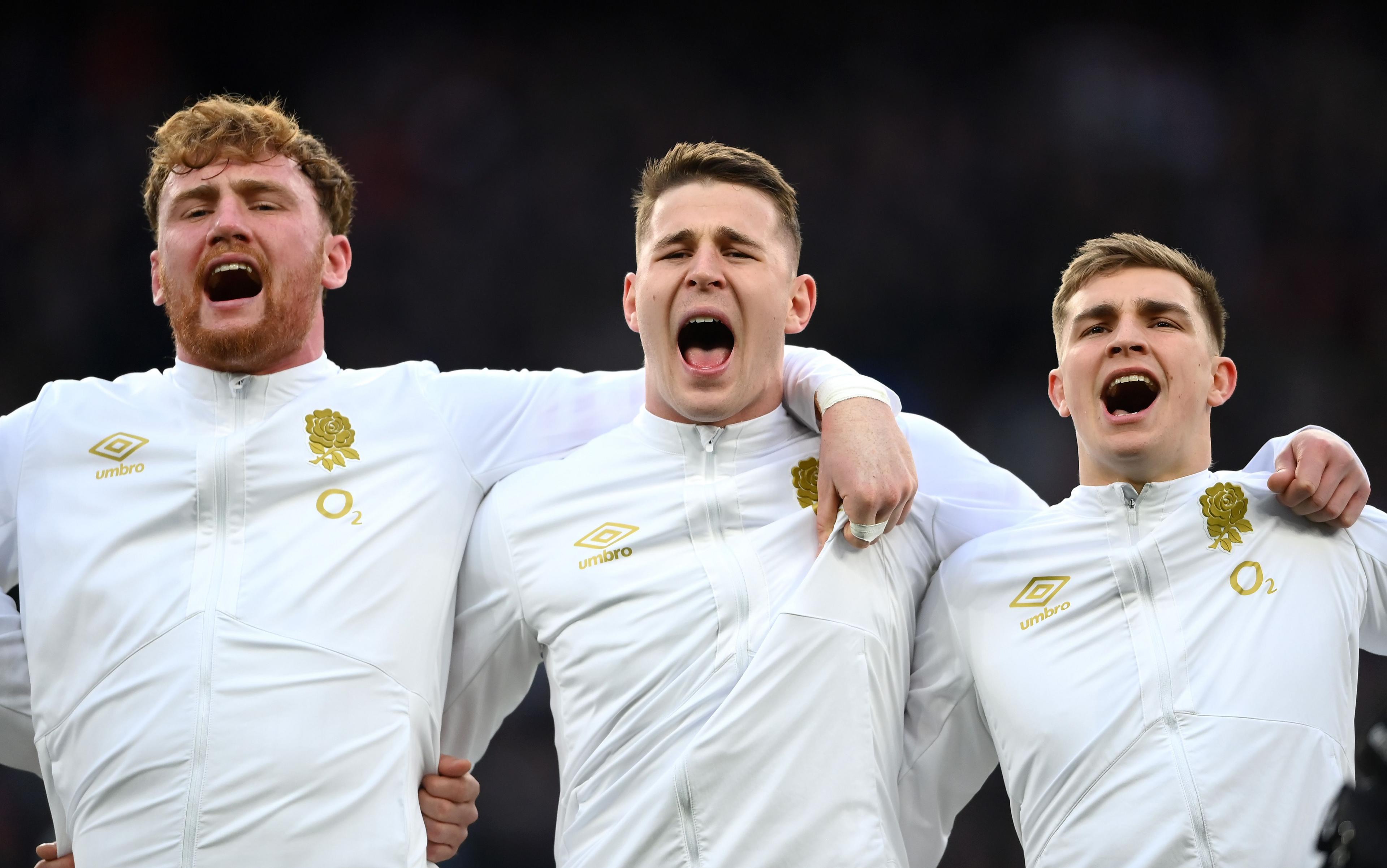 Three Tigers players wearing white shirts with gold logos and singing.