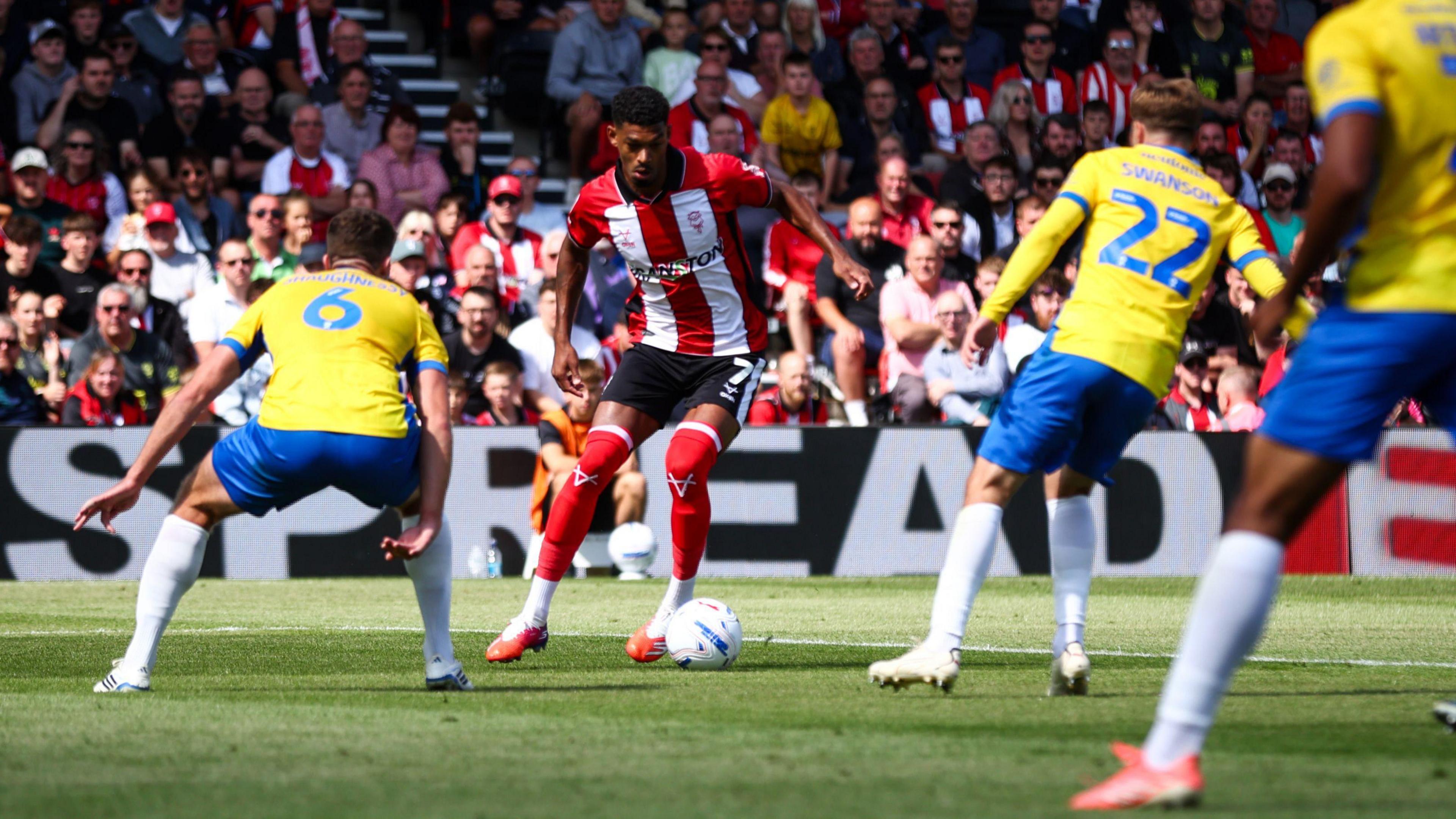 Lincoln City's Reeco Hackett-Fairchild under pressure on the ball by Portsmouth players during their Championship game on Saturday.