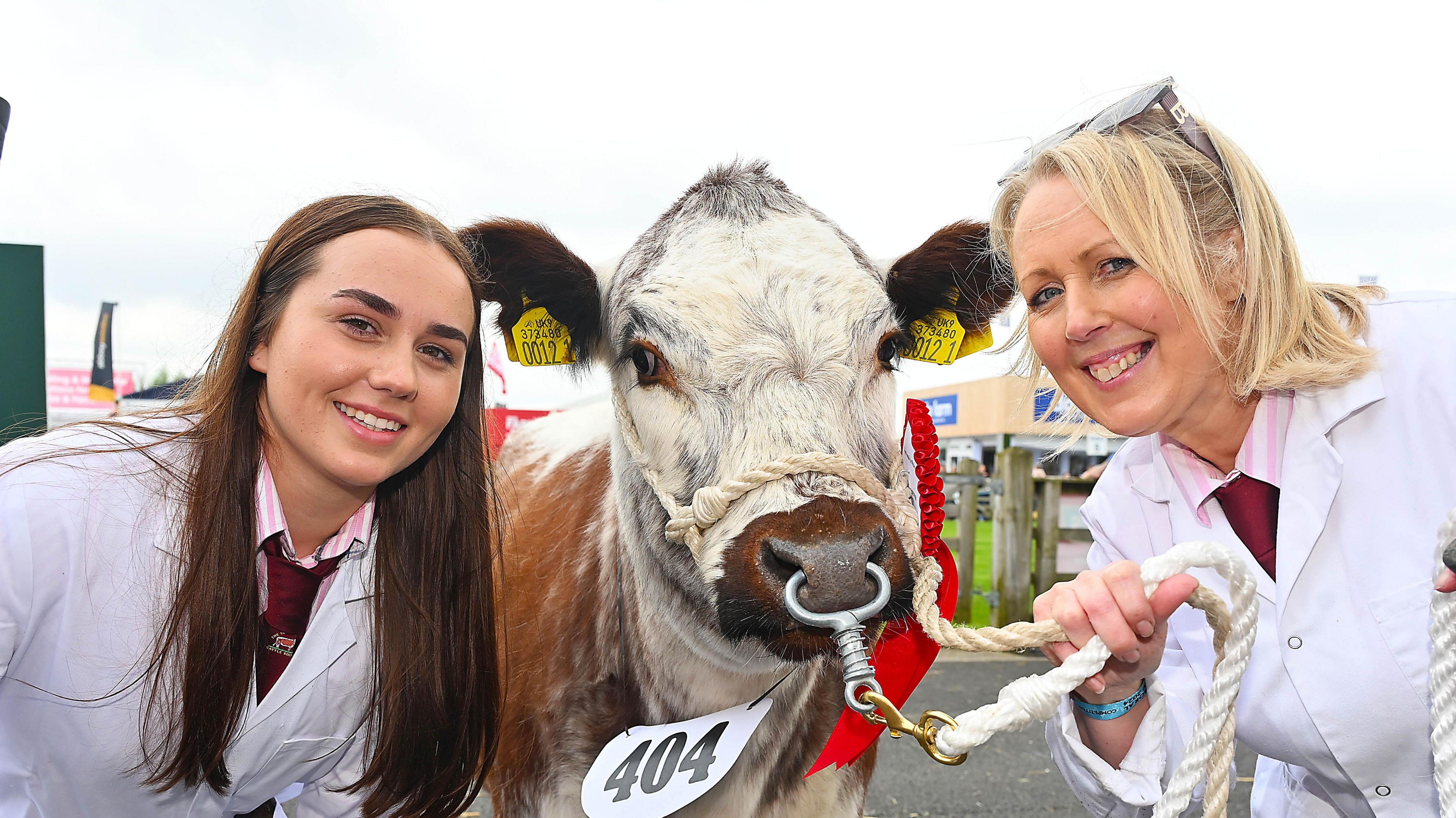 two women posing with a bull