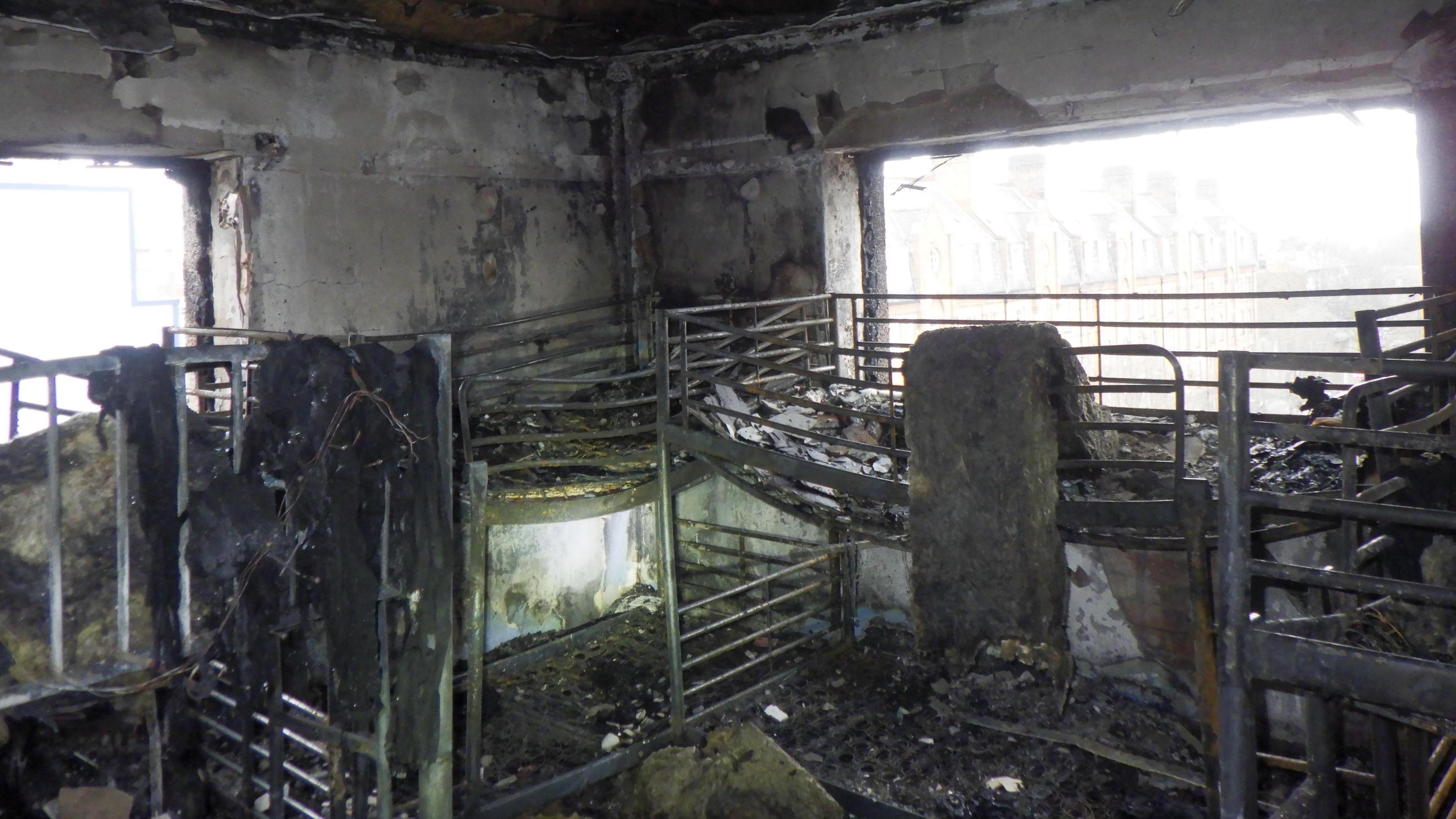 The burnt interior of one of the rooms, with multiple beds. 