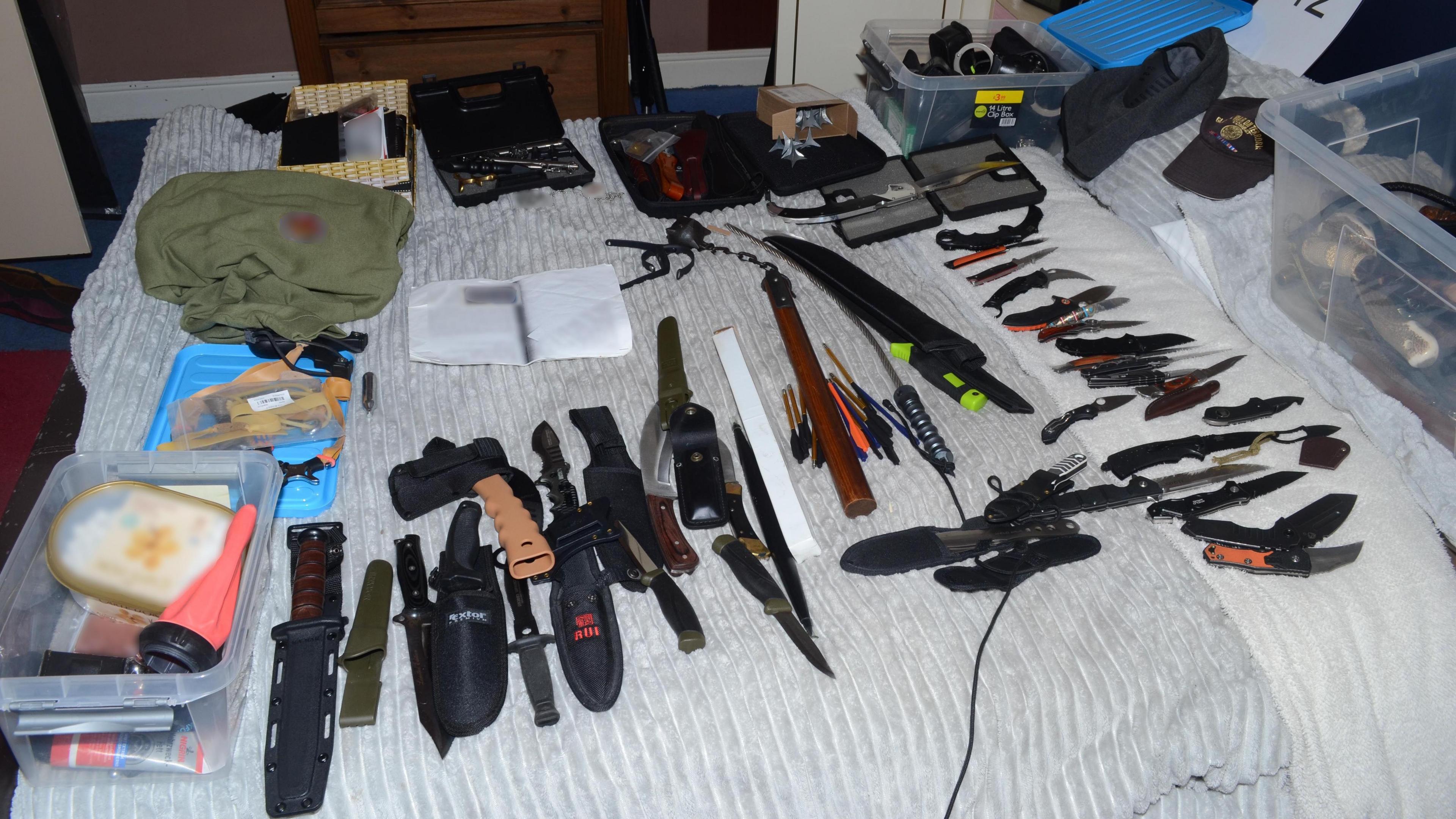 Dozens of dangerous blades are laid out on a bed