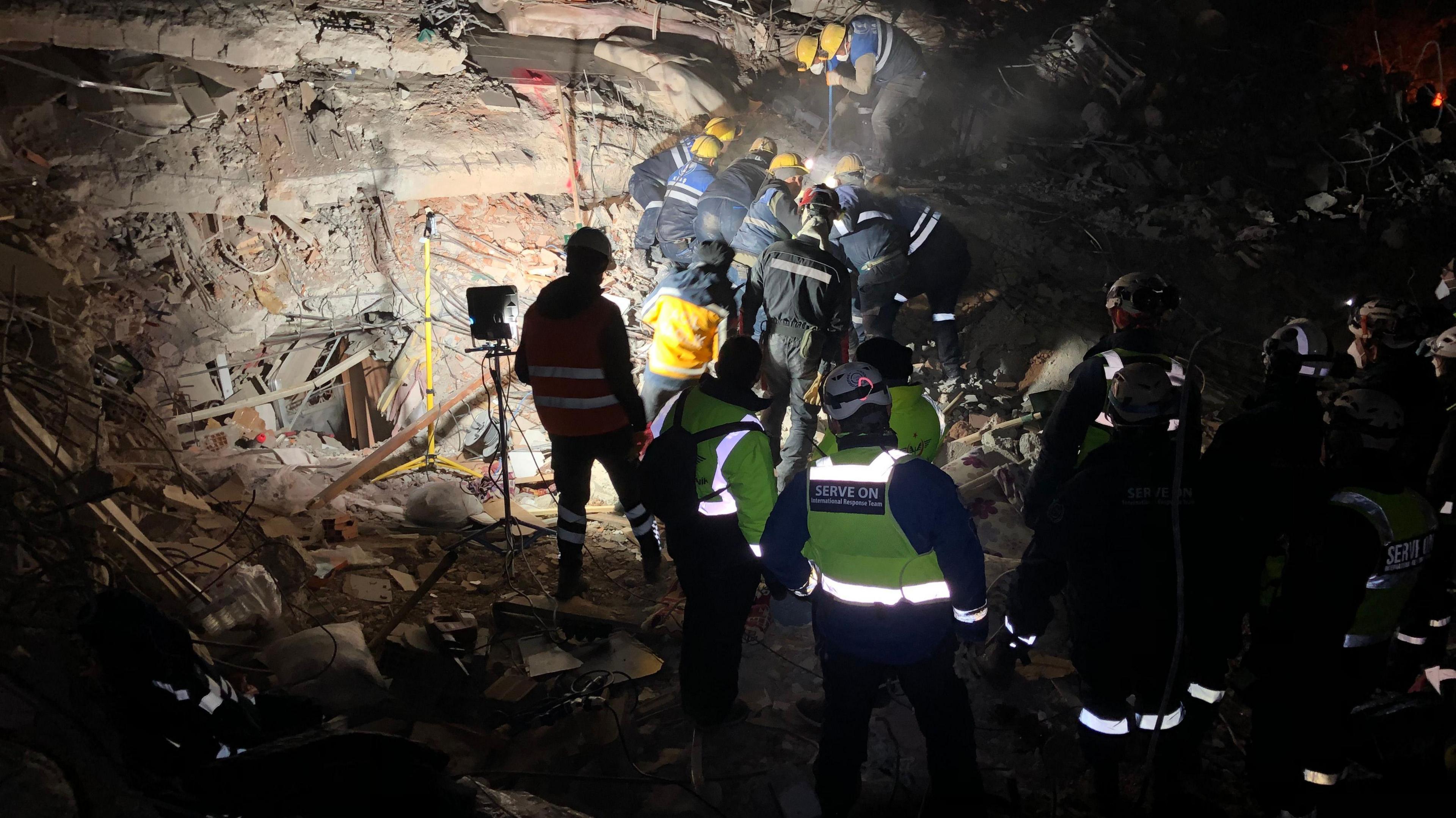 Volunteers attempting to rescue someone from rubble at night