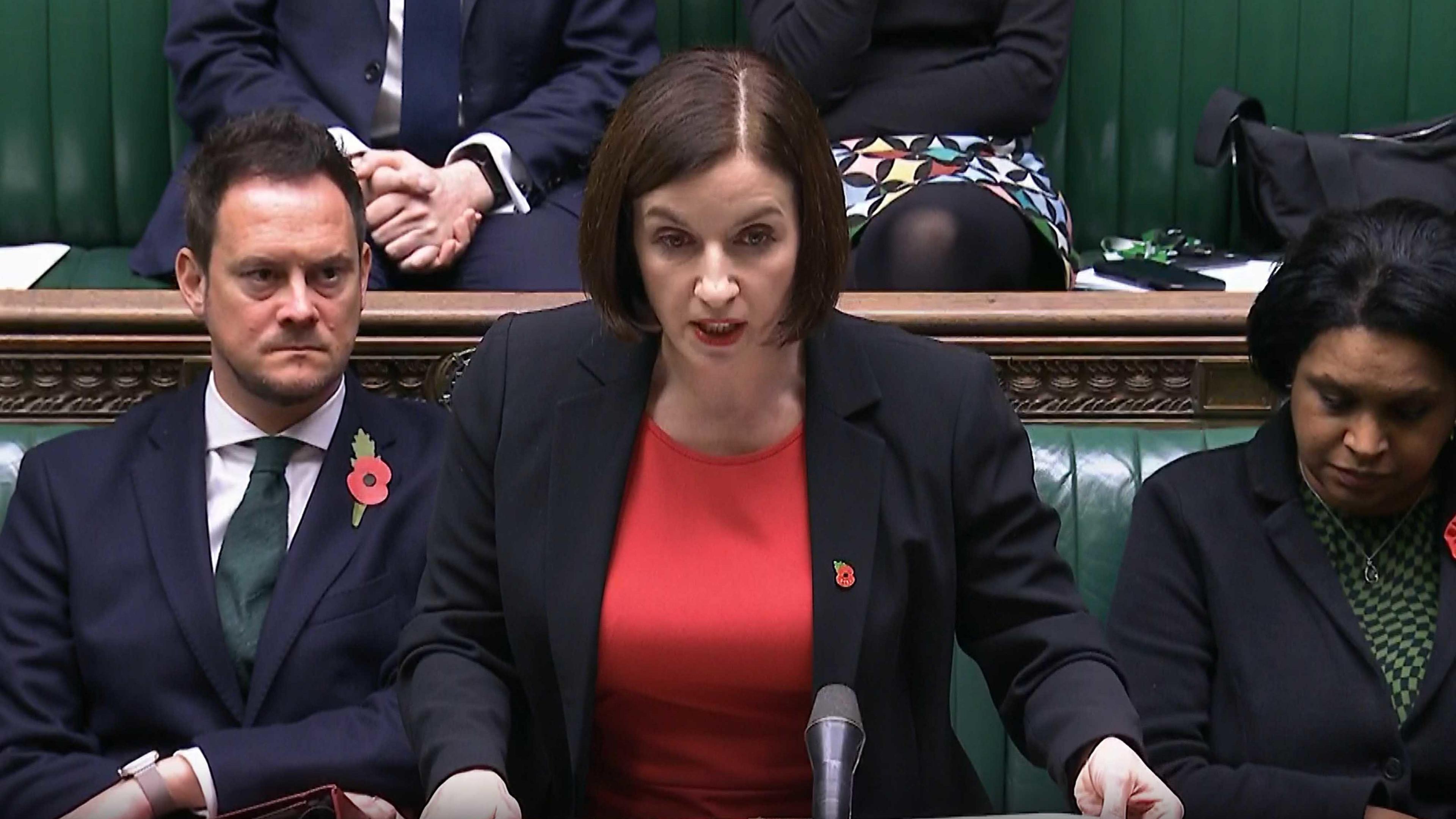 Education Secretary Bridget Phillipson. She is speaking in the House of Commons. She is wearing a red top under a black blazer. MPs are sitting behind her and beside her on the Commons benches.