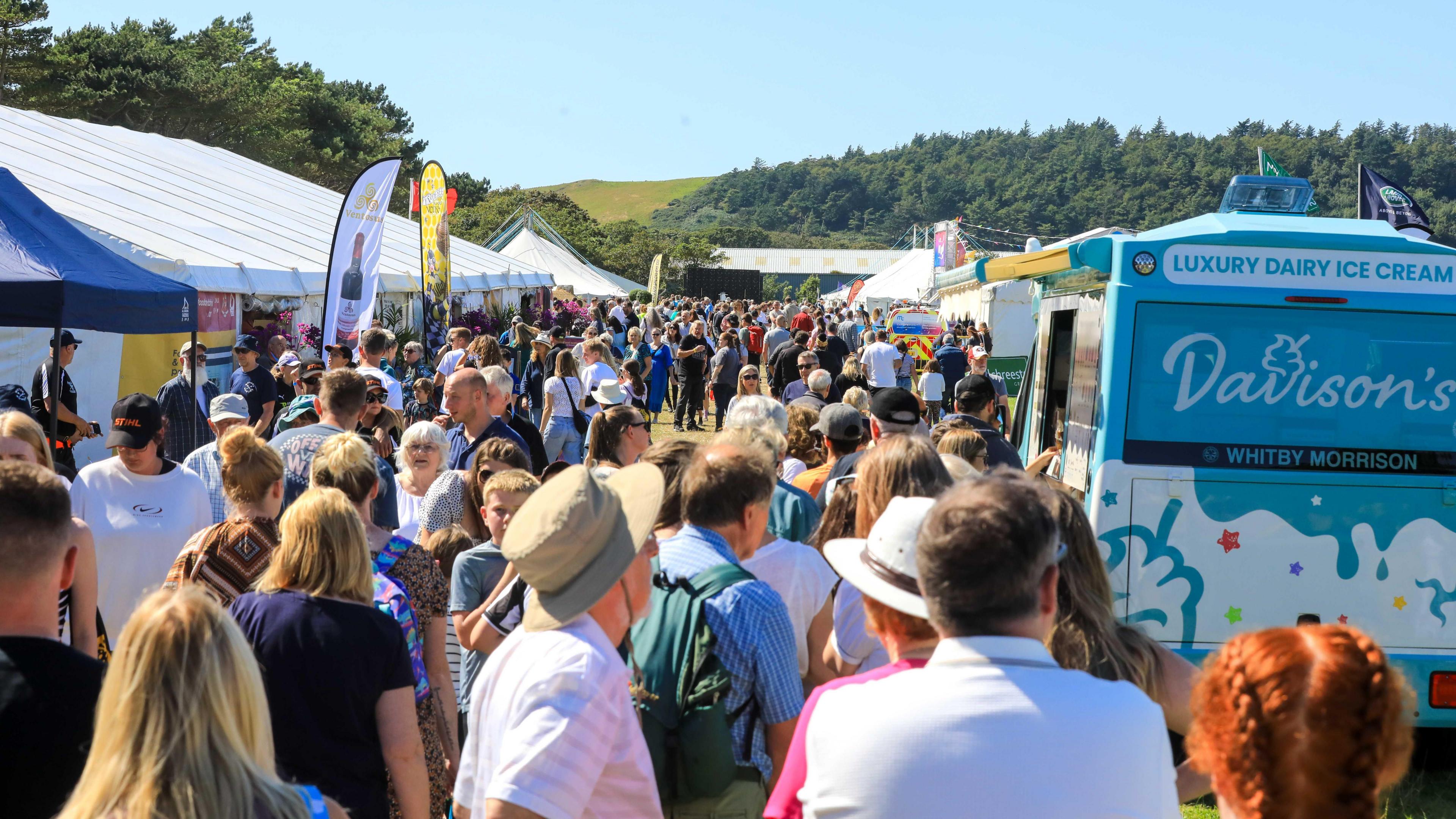 Large crowds amongst trade stands on a sunny day.