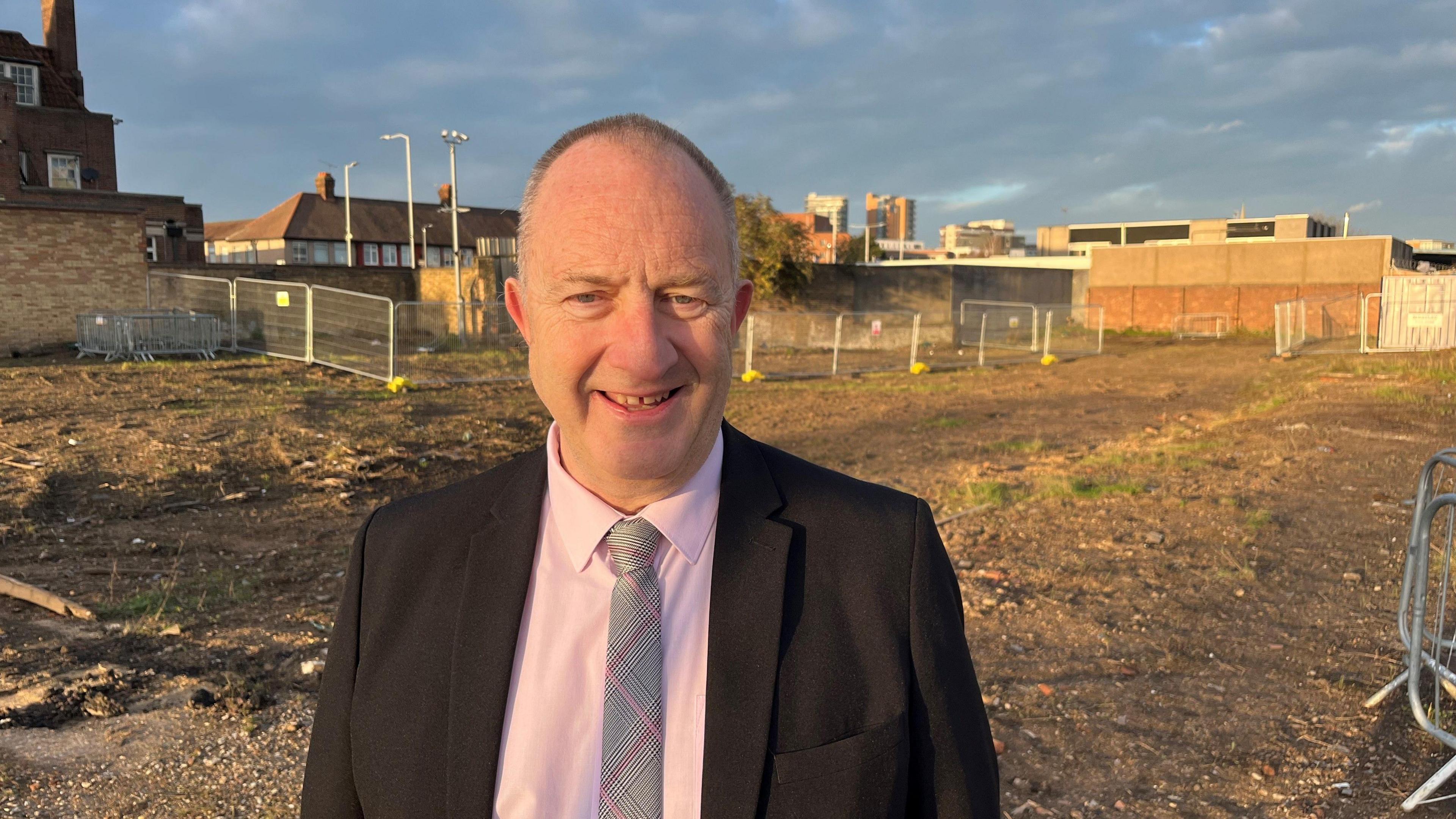 Head and shoulders picture of Cllr Ray Morgon, leader of Havering Council, on an empty plot of land in Romford that is waiting to be developed