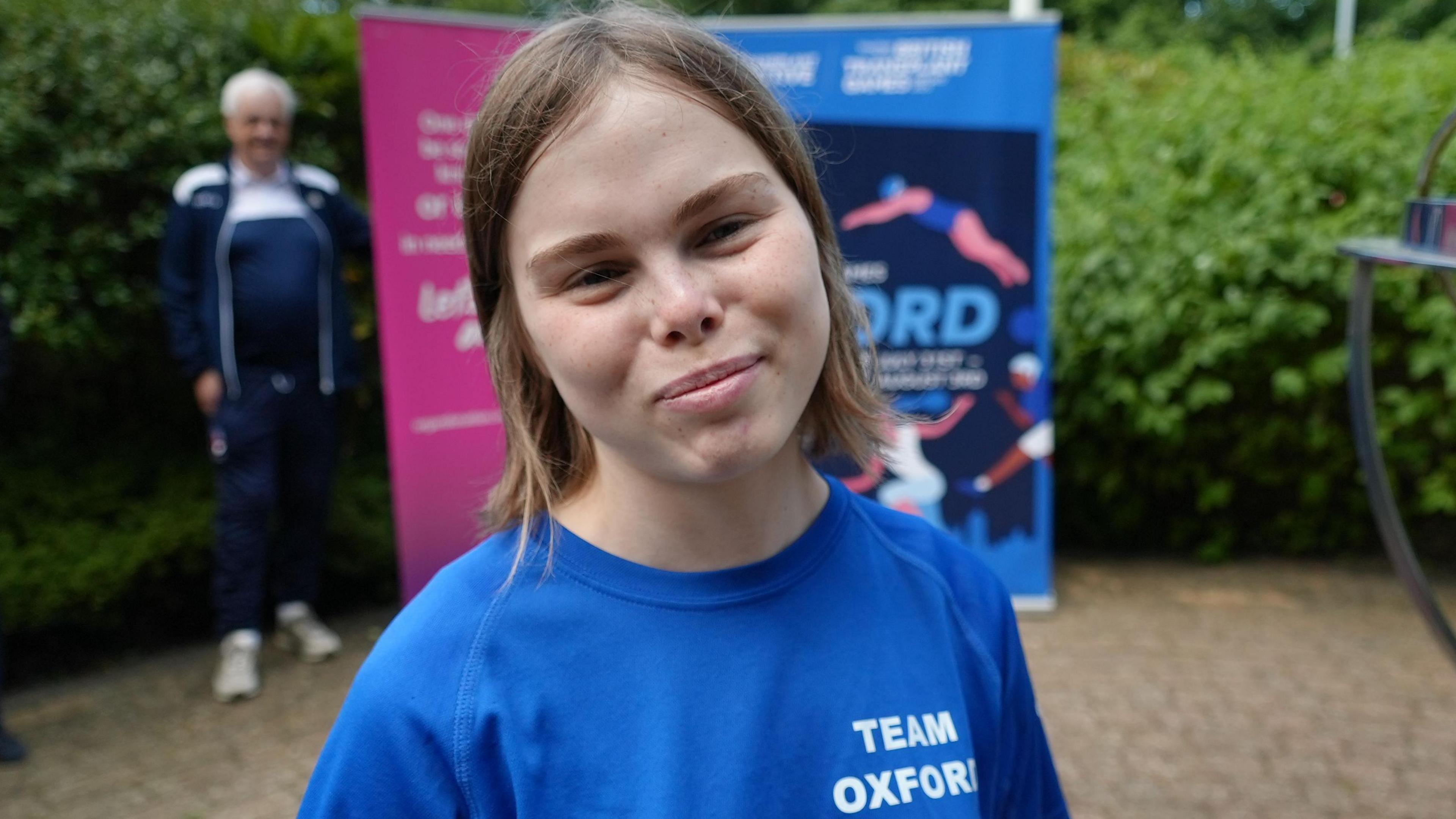 Blossom martin has medium length brown hair and is wearing a blue t-shirt.