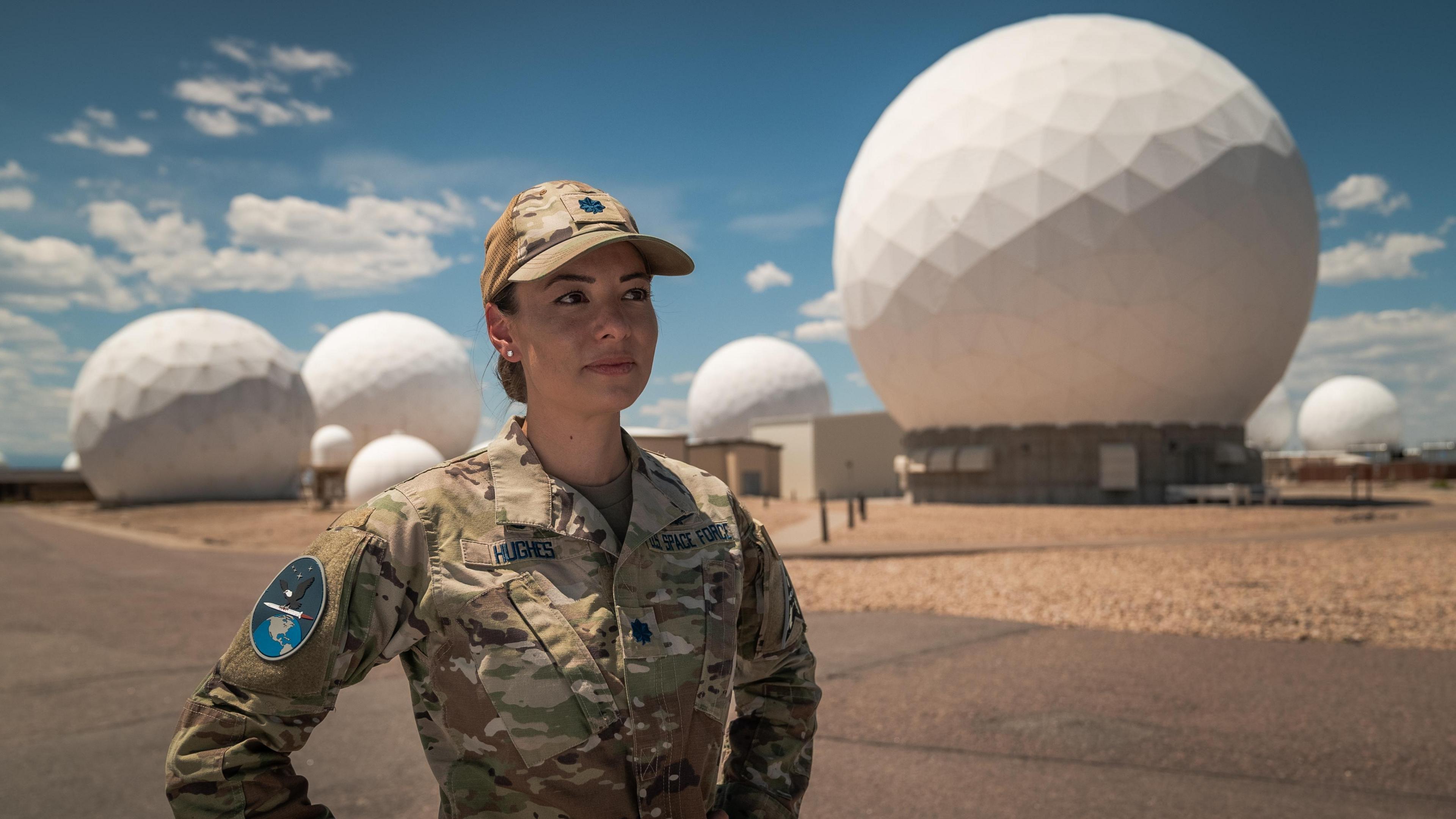 Lt Col Ann Hughes standing in front of a giant radar array in Colorado