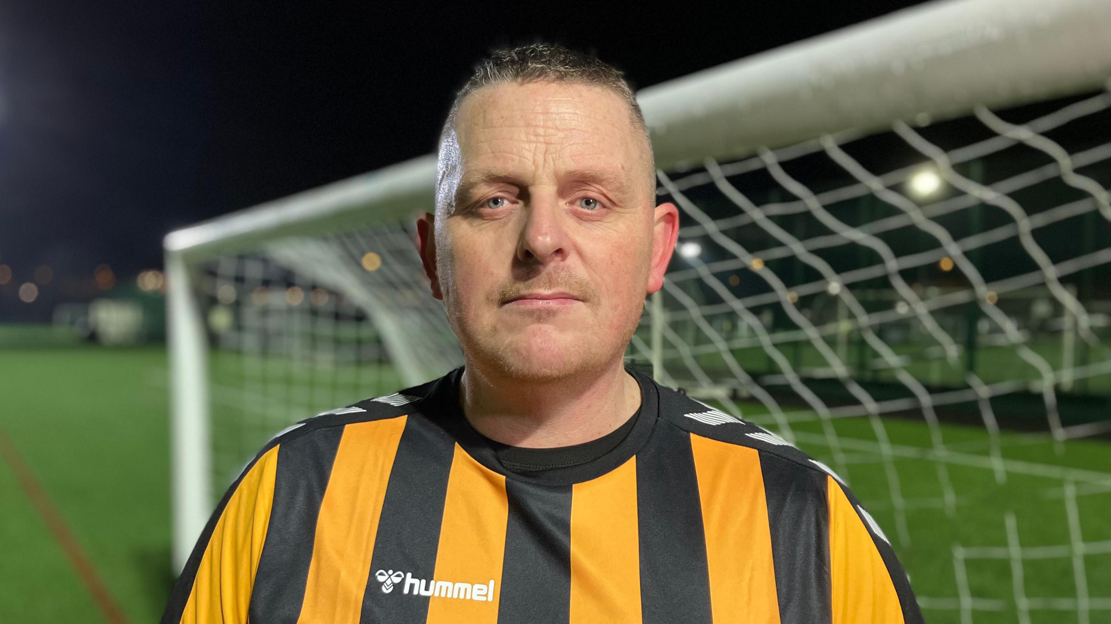 Football player Chris Wilbraham looks into the camera while standing in front of goalposts