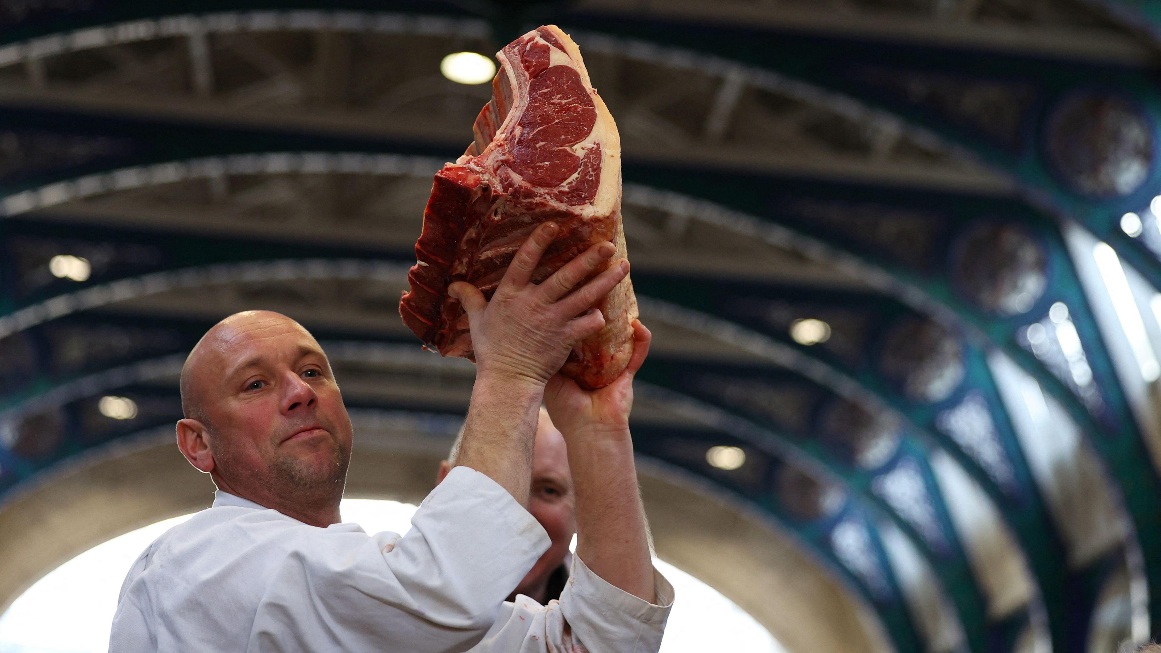 Seller holds up prime cut of meat