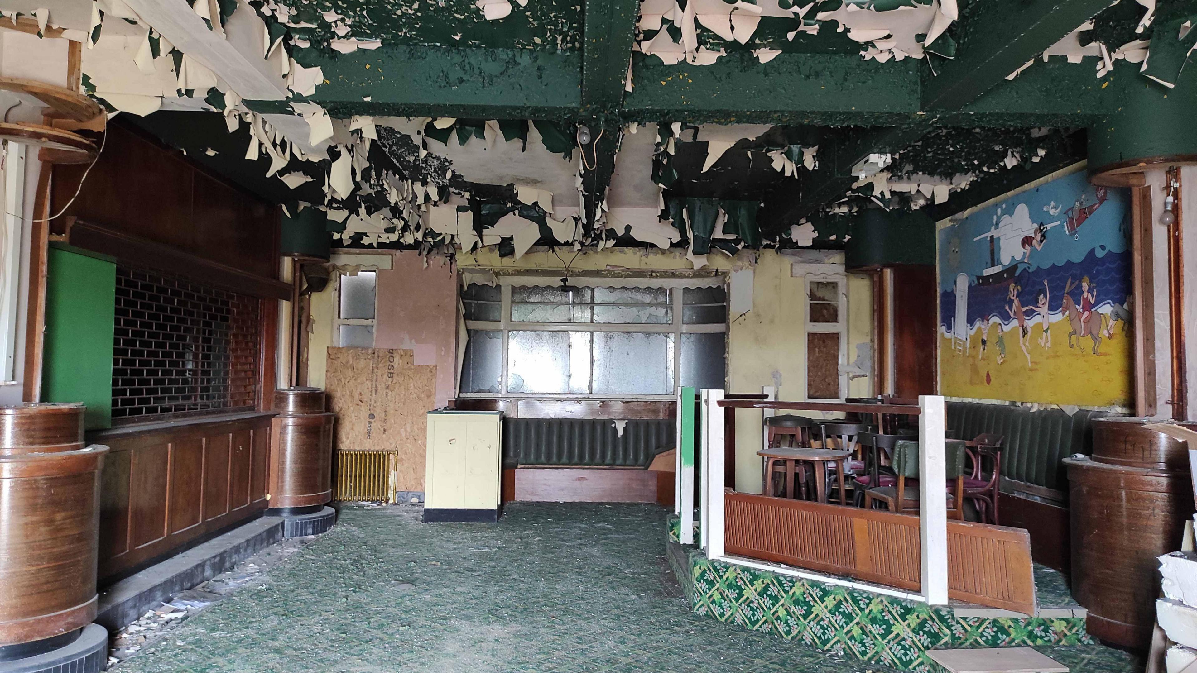 The inside of the Iron Duke pub. Green paint can be seen peeling from the ceiling. The rest of the interior is looking very dilapidated