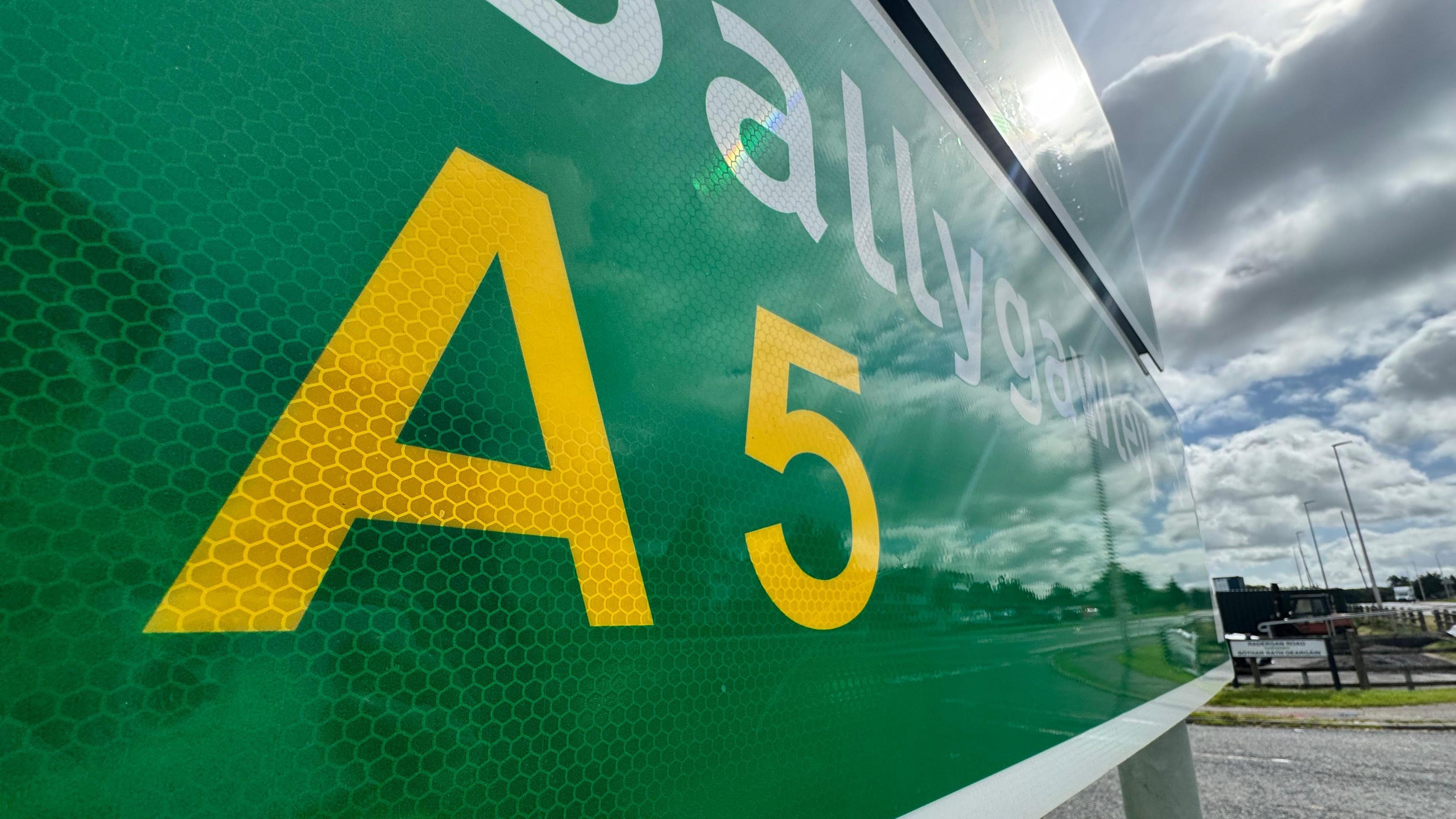 A green road sign with A5 written in yellow
