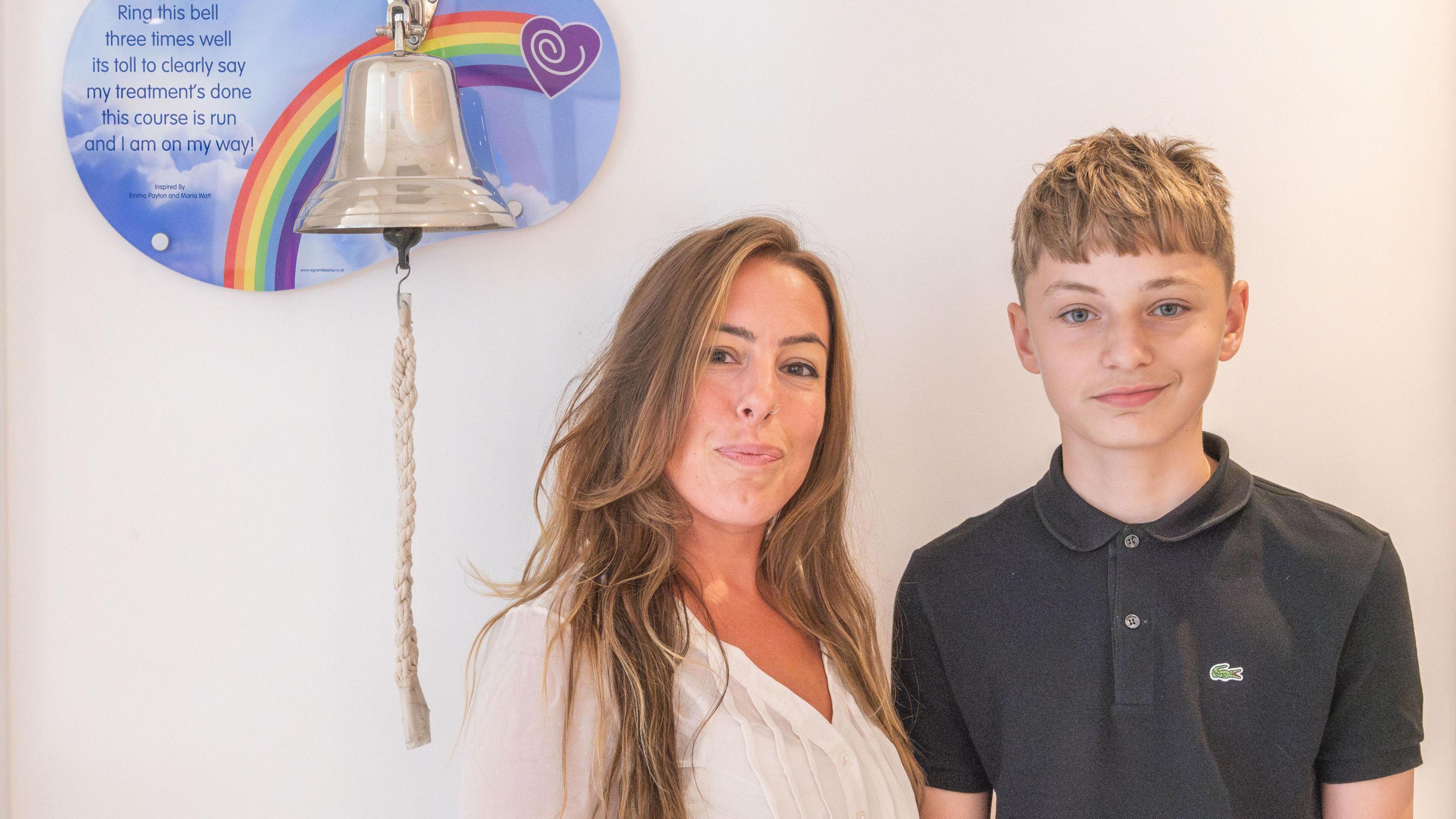 An image of a woman and a young man stood next to a bell that is rung when you finish cancer treatment 