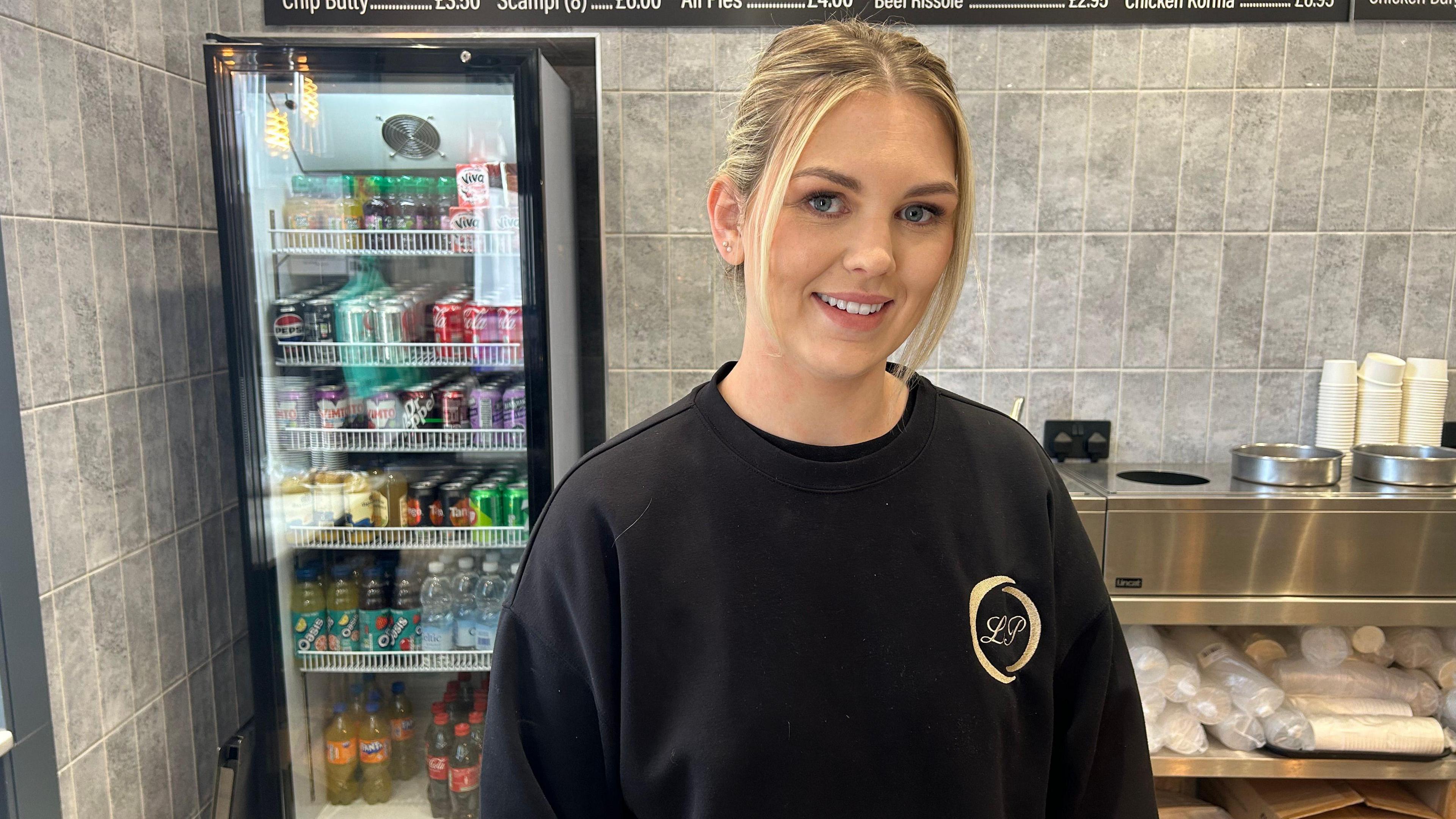 Anwen Haf Davies tu ôl i'r cownter yn siop sglodion Llond Plat