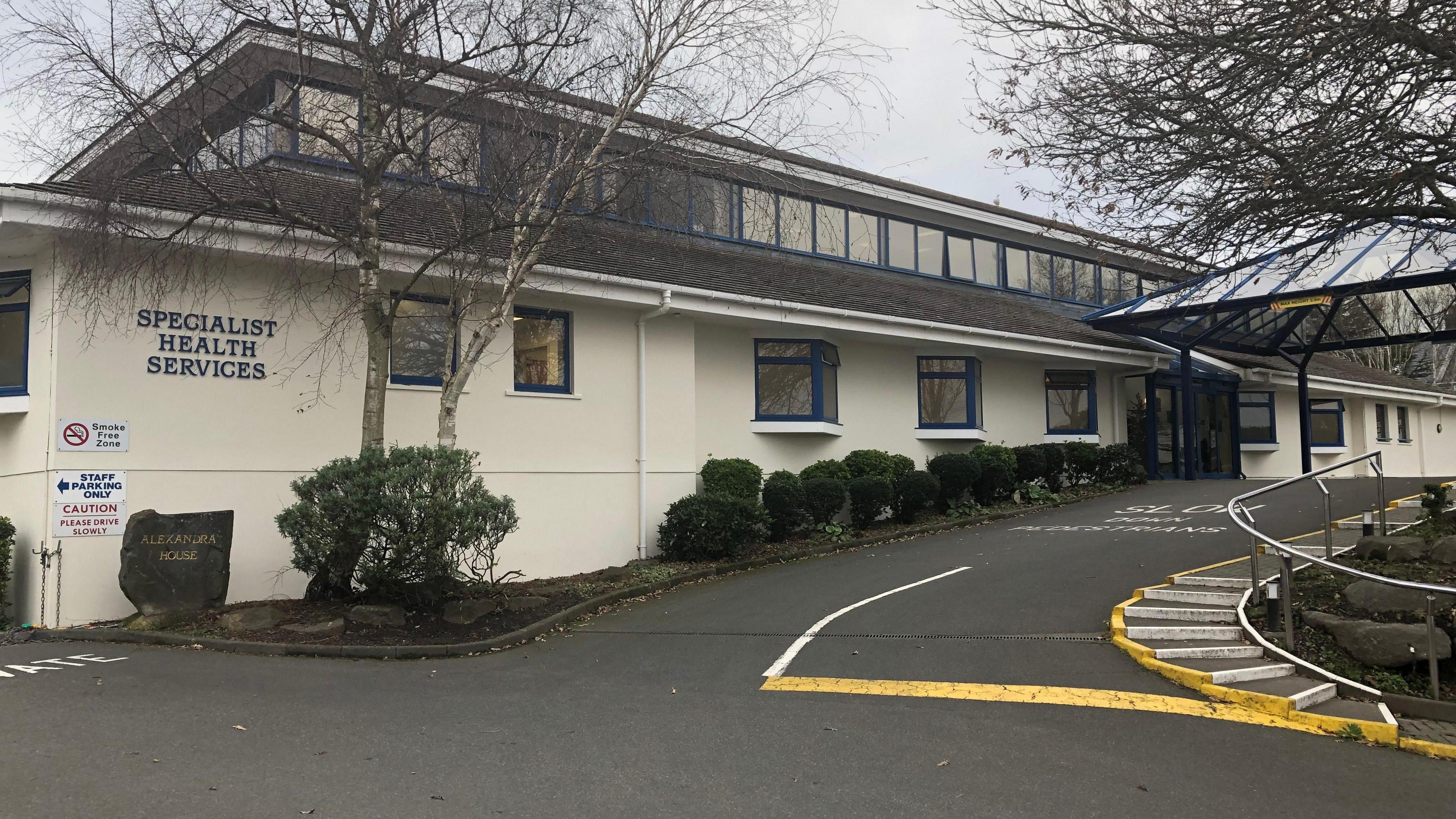 Guernsey's Medical Specialist Group - A creamy yellow building with a bare tree in front of it. On the wall it says Specialist Health Services. 