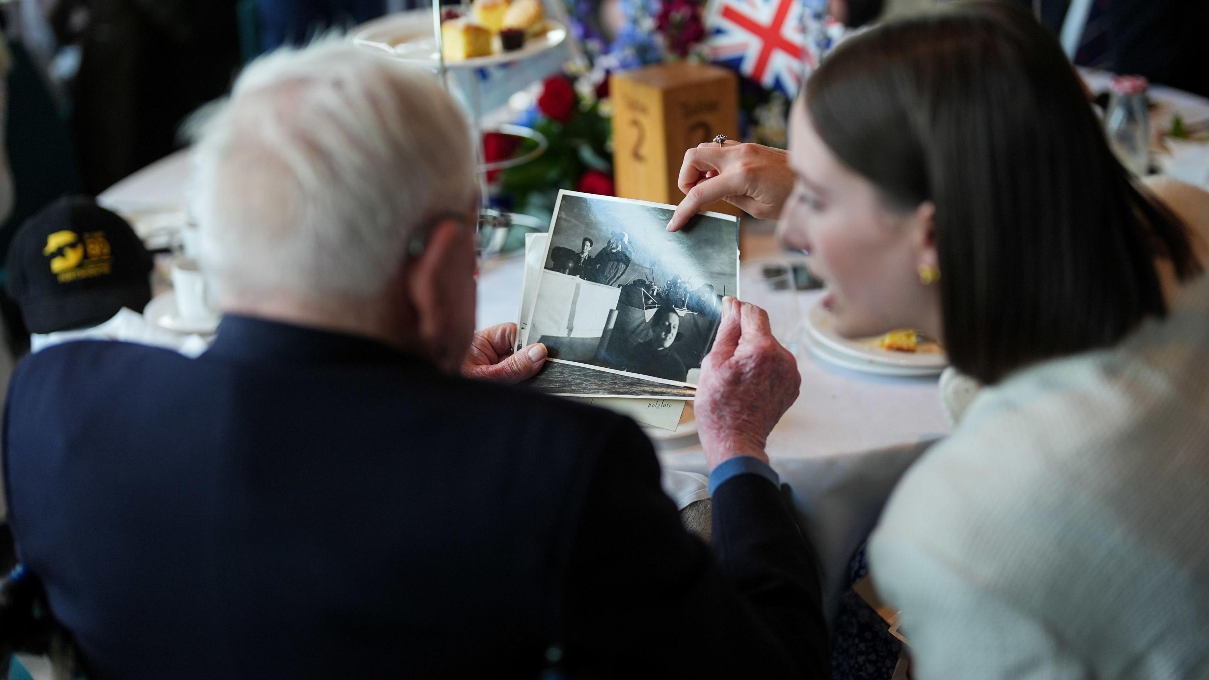 The back of a man and woman as they both look at old black and white photographs