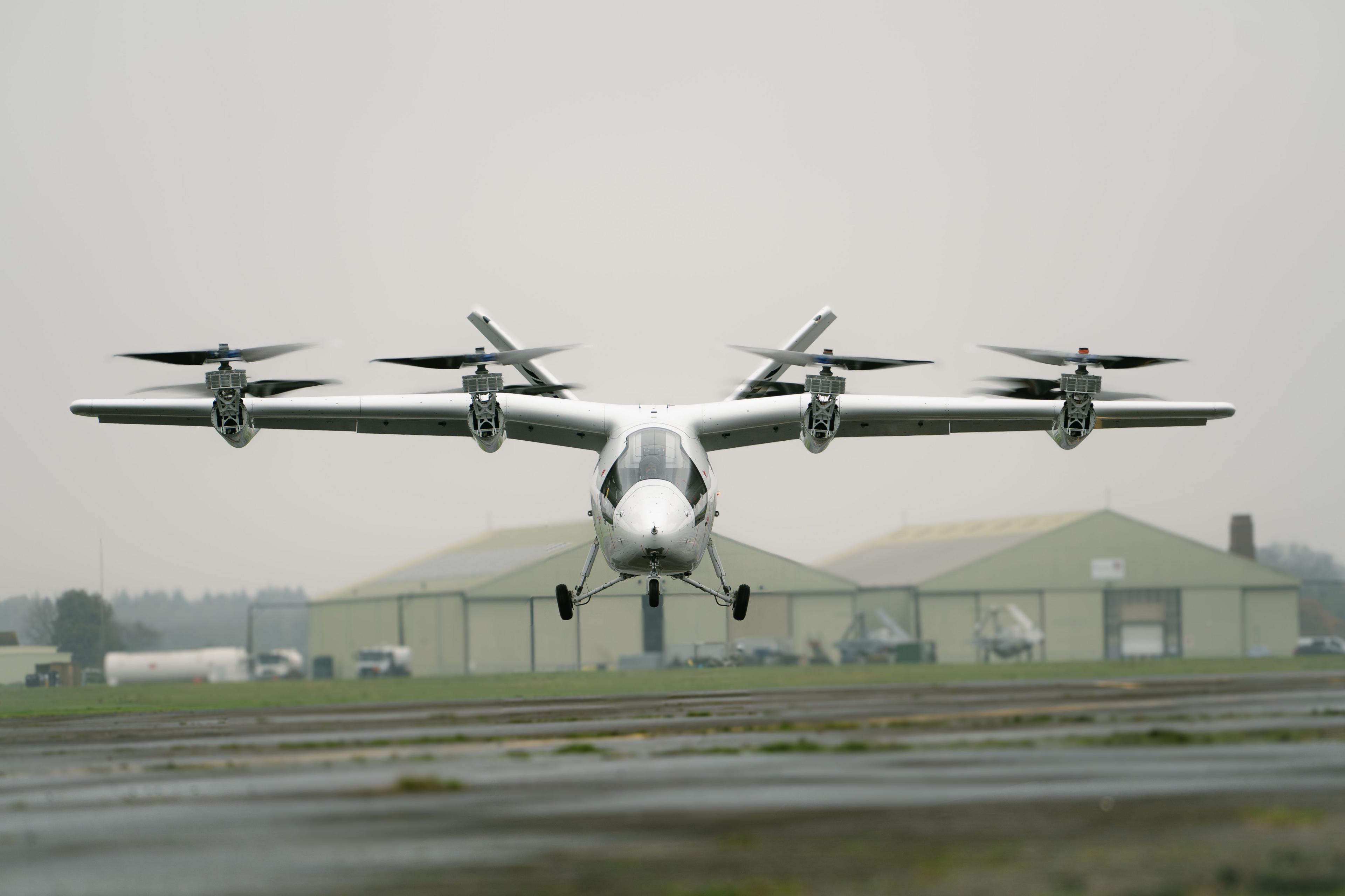 The aircraft seen from the front, with its two wings above the fuselage and eight rotors mounted front and back.