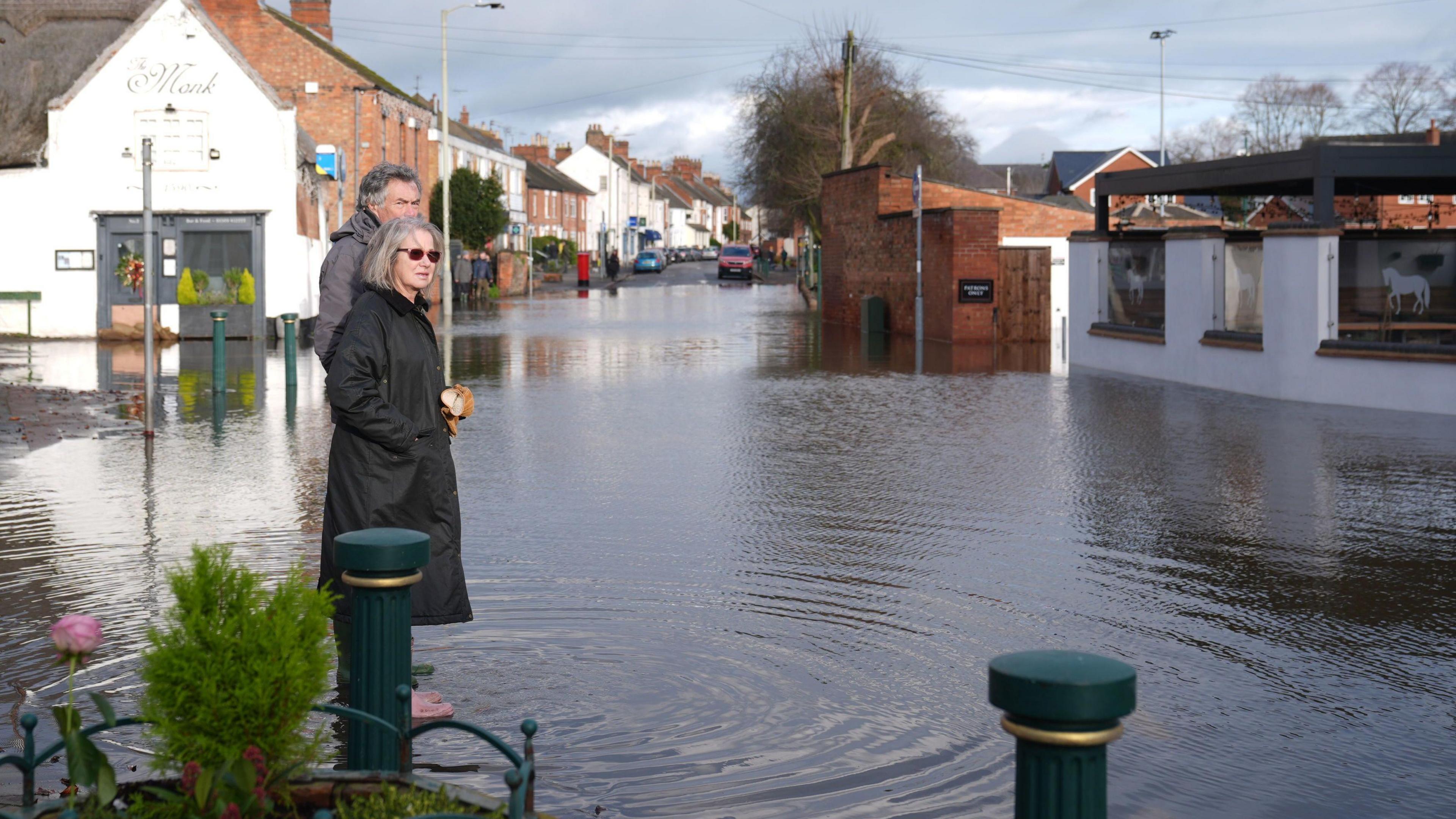 A man and woman stood in floodwater in the village of Quorn, Leicestershire. 