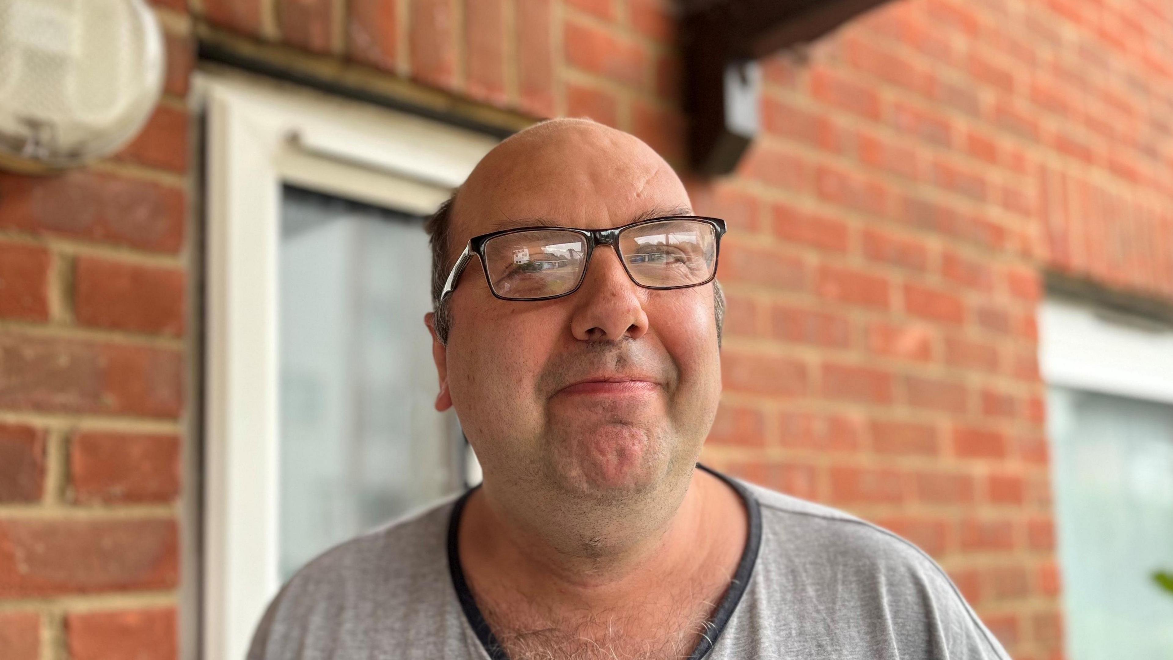 Mark Green smiling at the camera standing next to his house