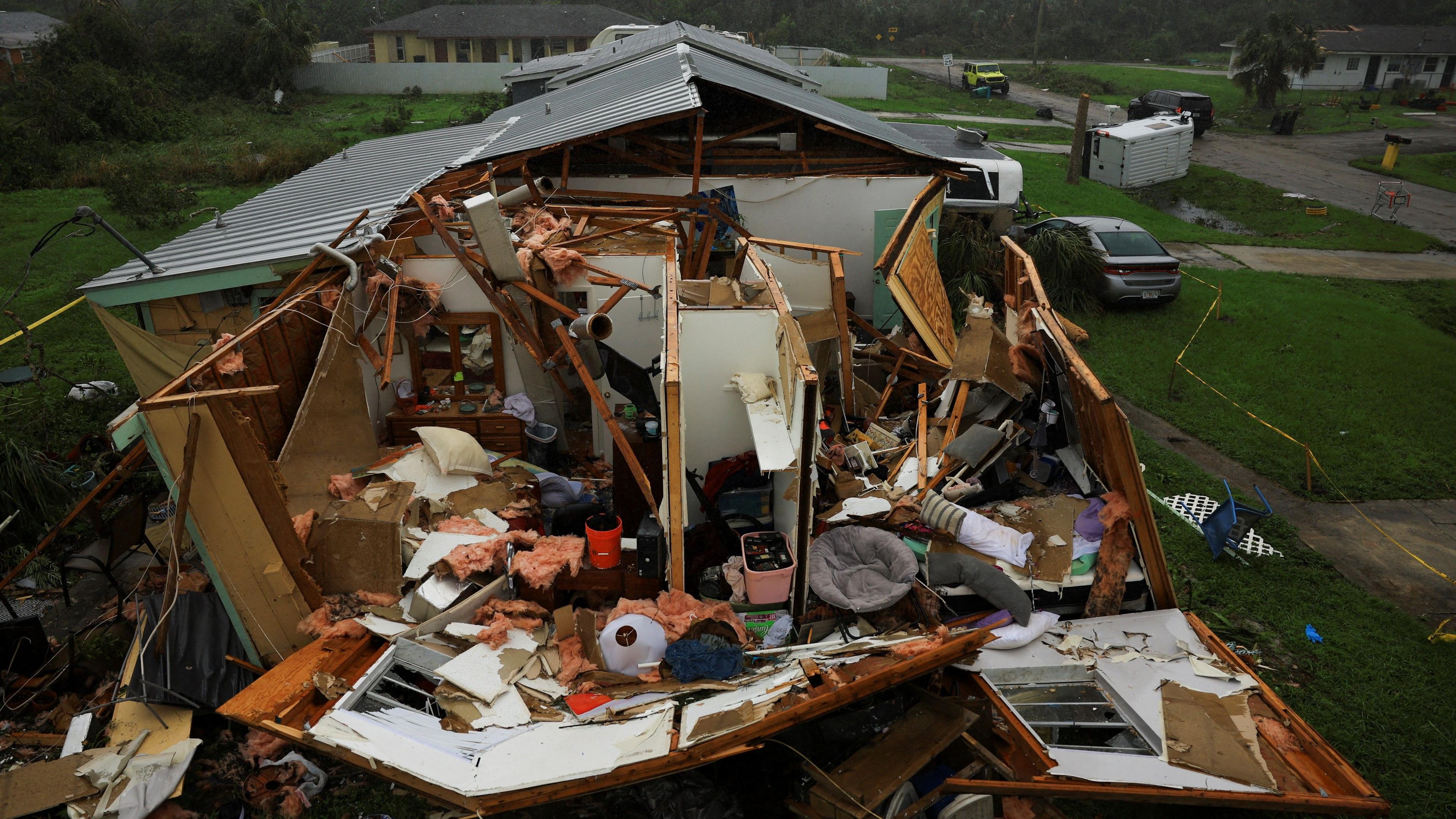 A home with the roof ripped off, walls missing or leaning dangerously, massive internal damage, and belongings strewn in and around the property