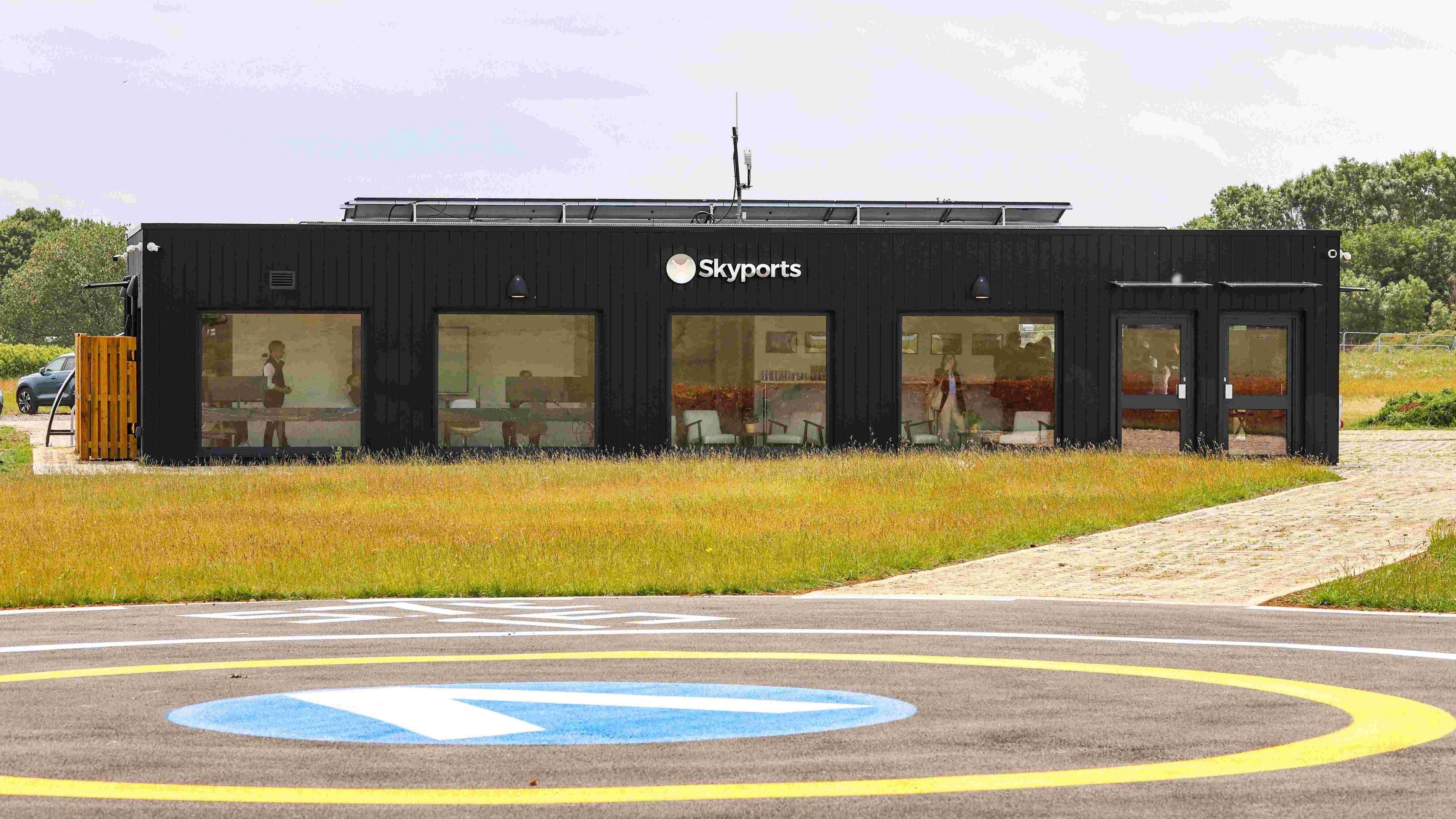 The Bicester Vertiport building exterior with Skyports logo. There is a roundabout in front of it.