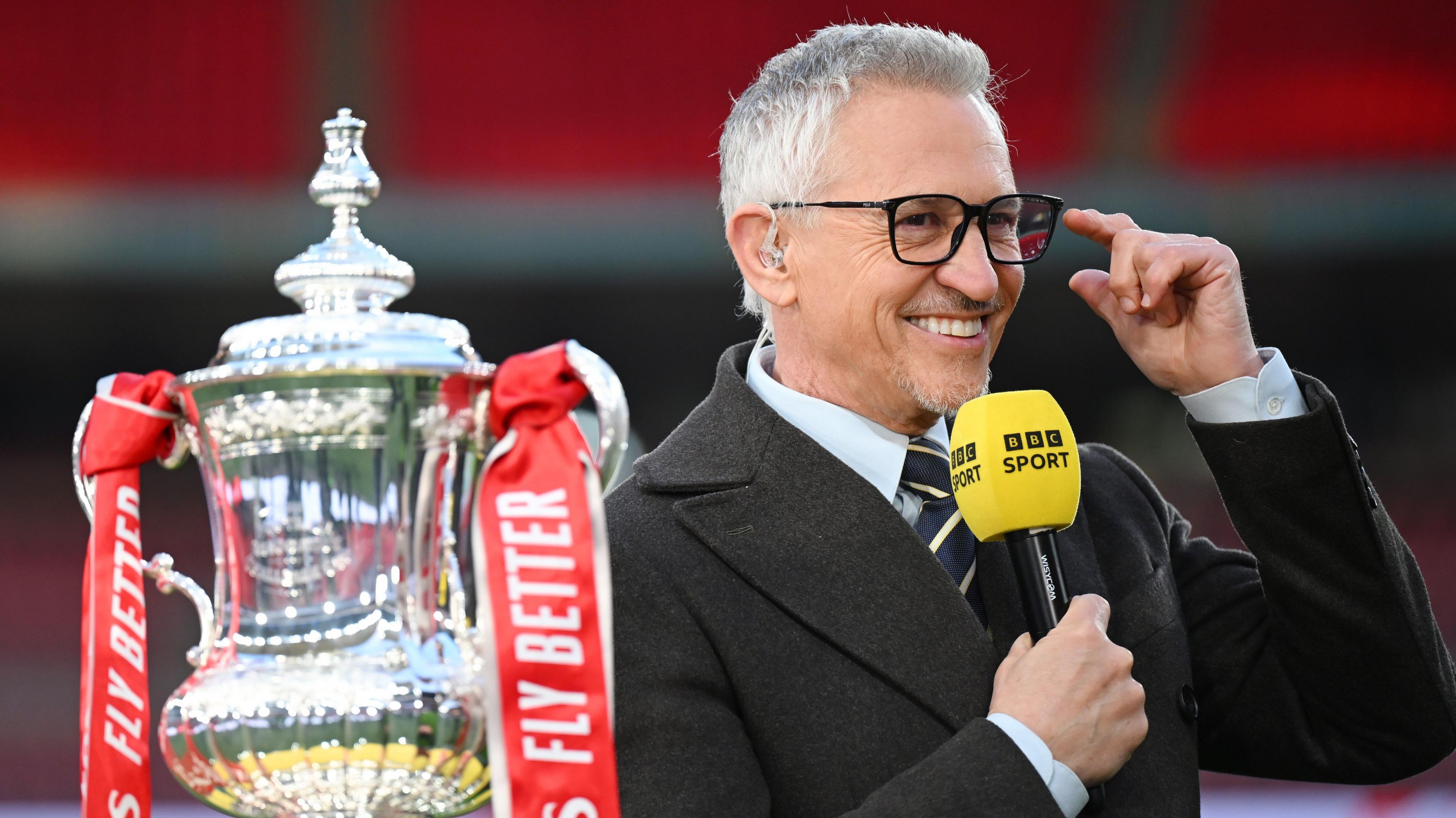 Gary Lineker smiles while holding a BBC Sport microphone