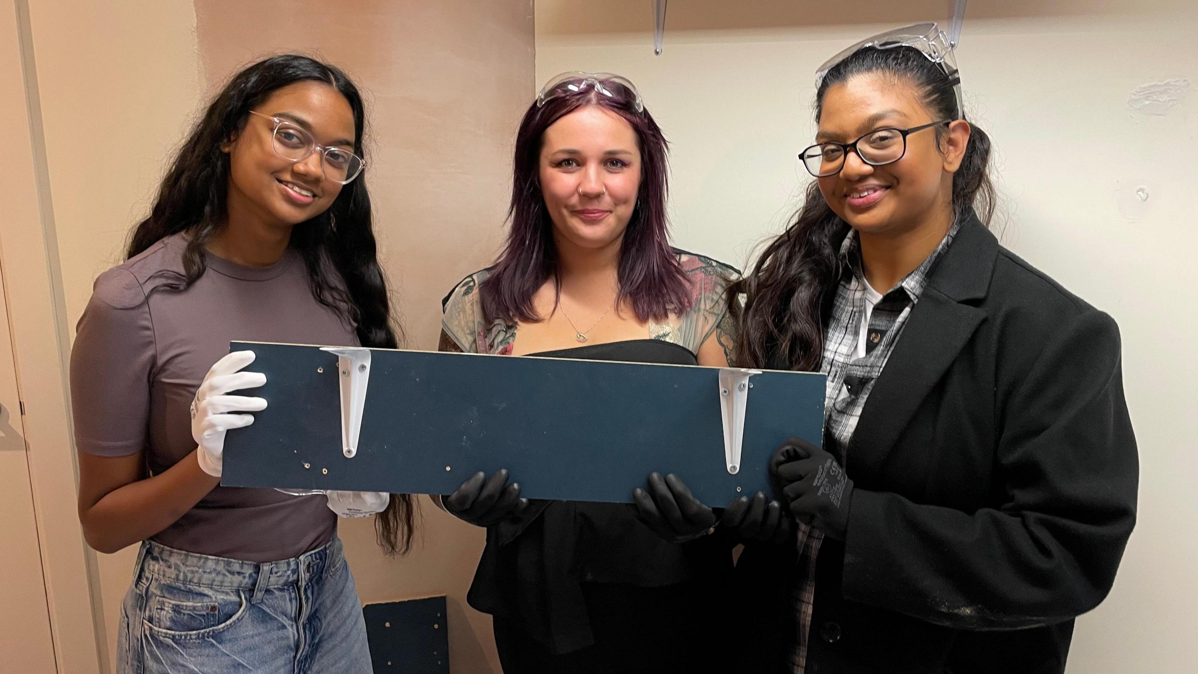 Three young women show the shelf they made at the Skills Hub