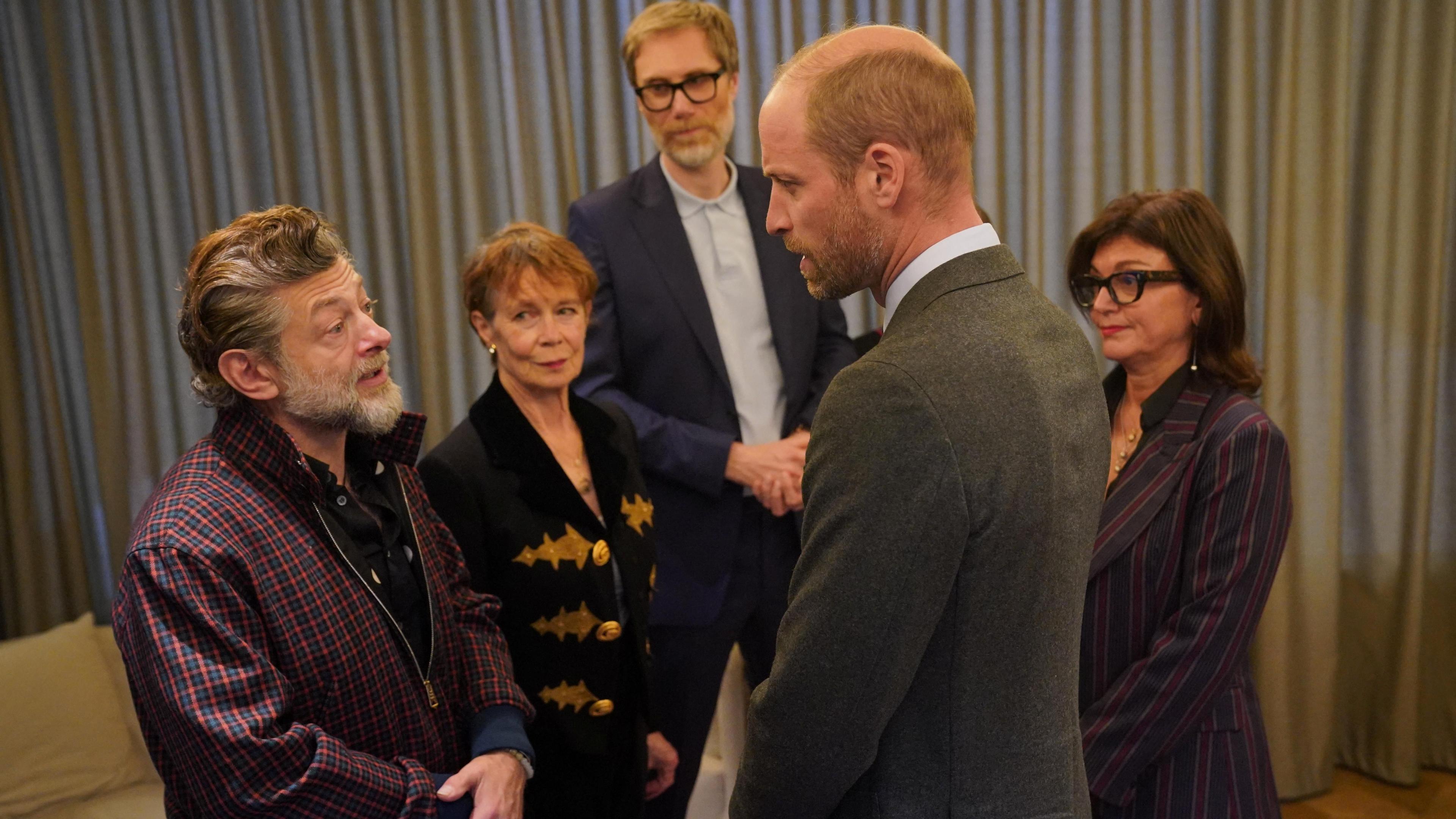 Prince William wearing a grey suit speaks to actor Andy Serkis as Celia Imrie, Stephen Merchant and Jane Milichip watch on