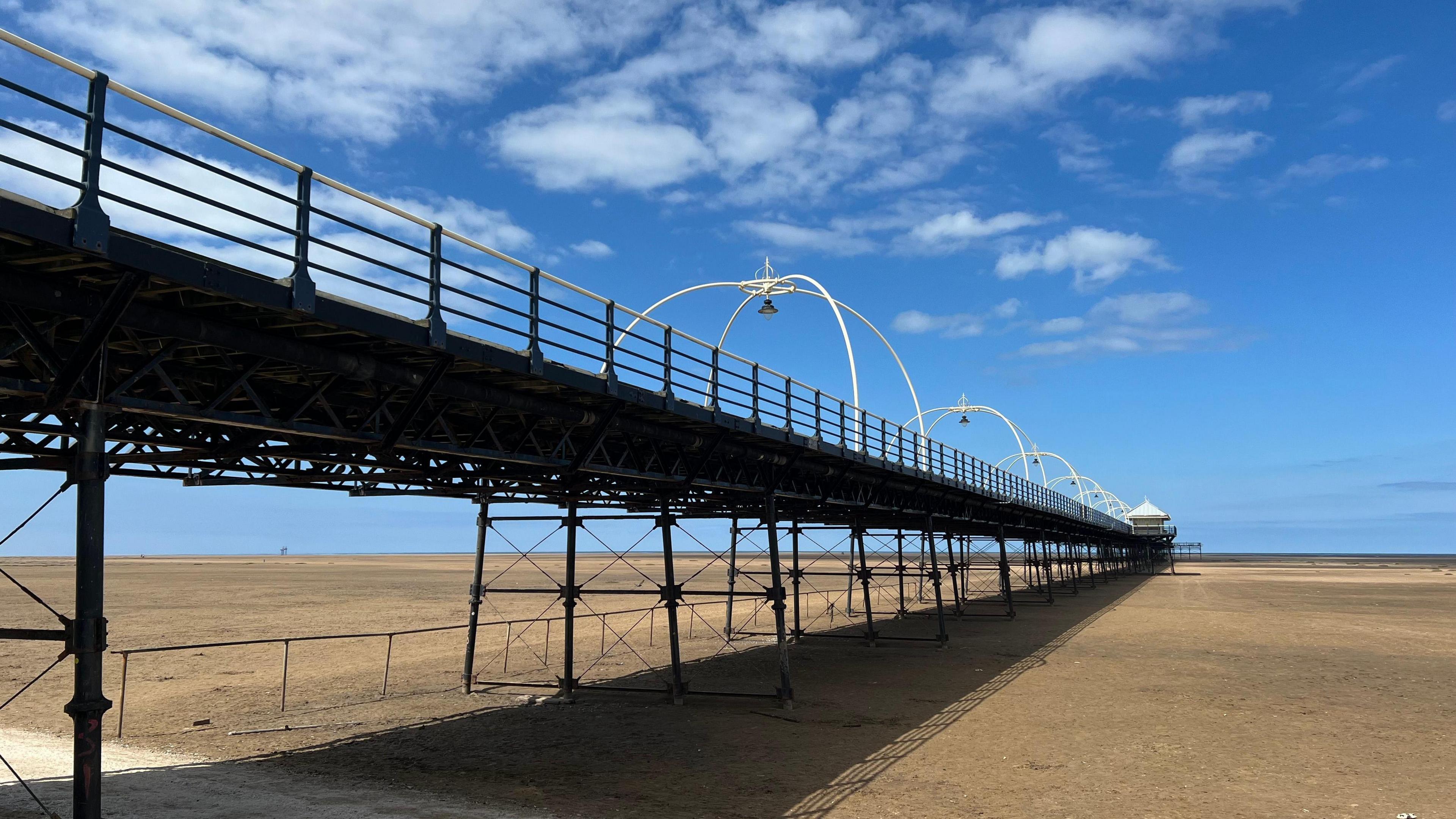 Southport Pier on a sunny day with blue skies. Taken from beneath the pier on the beach.