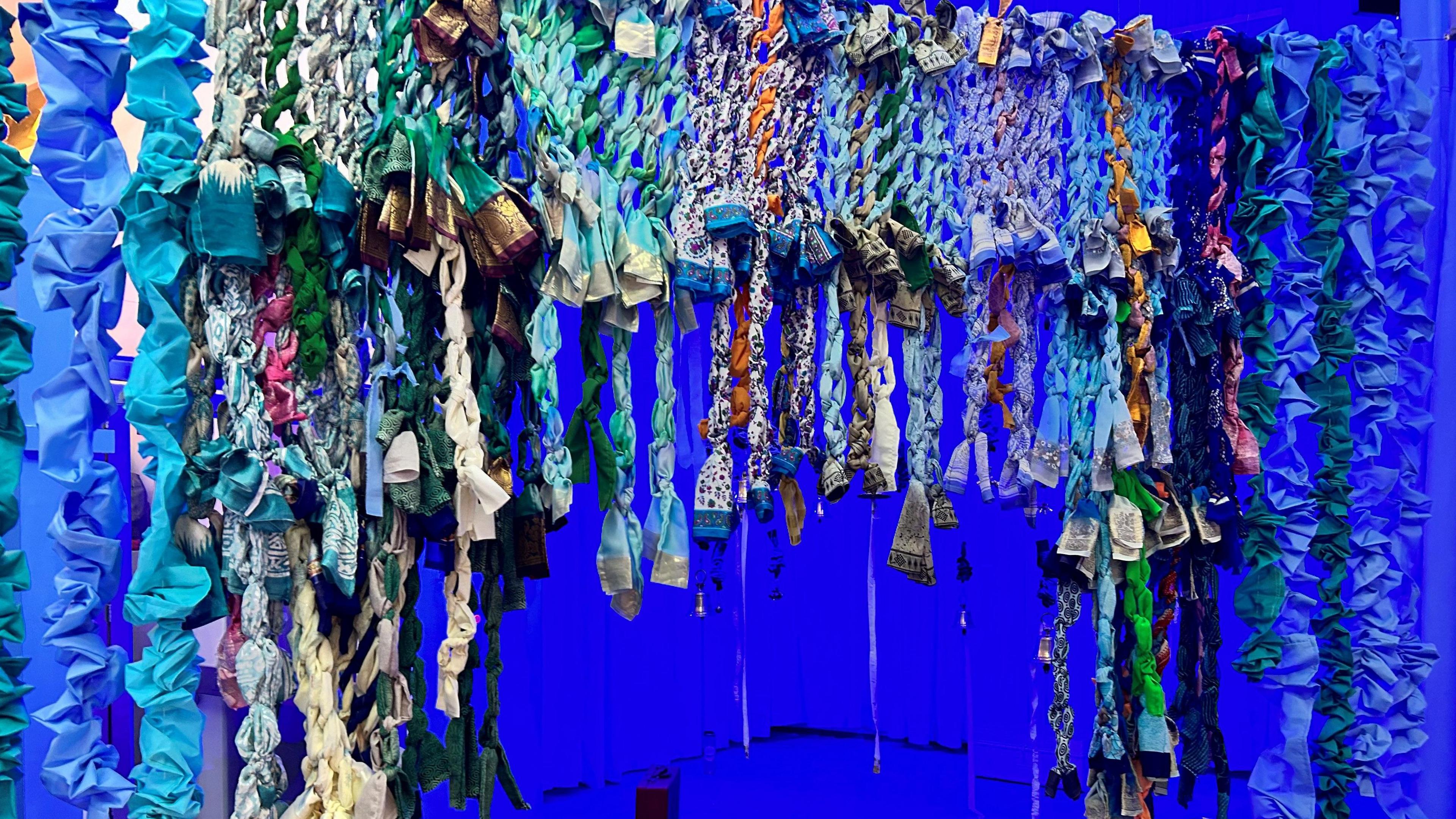 Sarees and other textiles are repurposed to make a curtain of blues and greens and many other colours to walk through at the exhibition. 