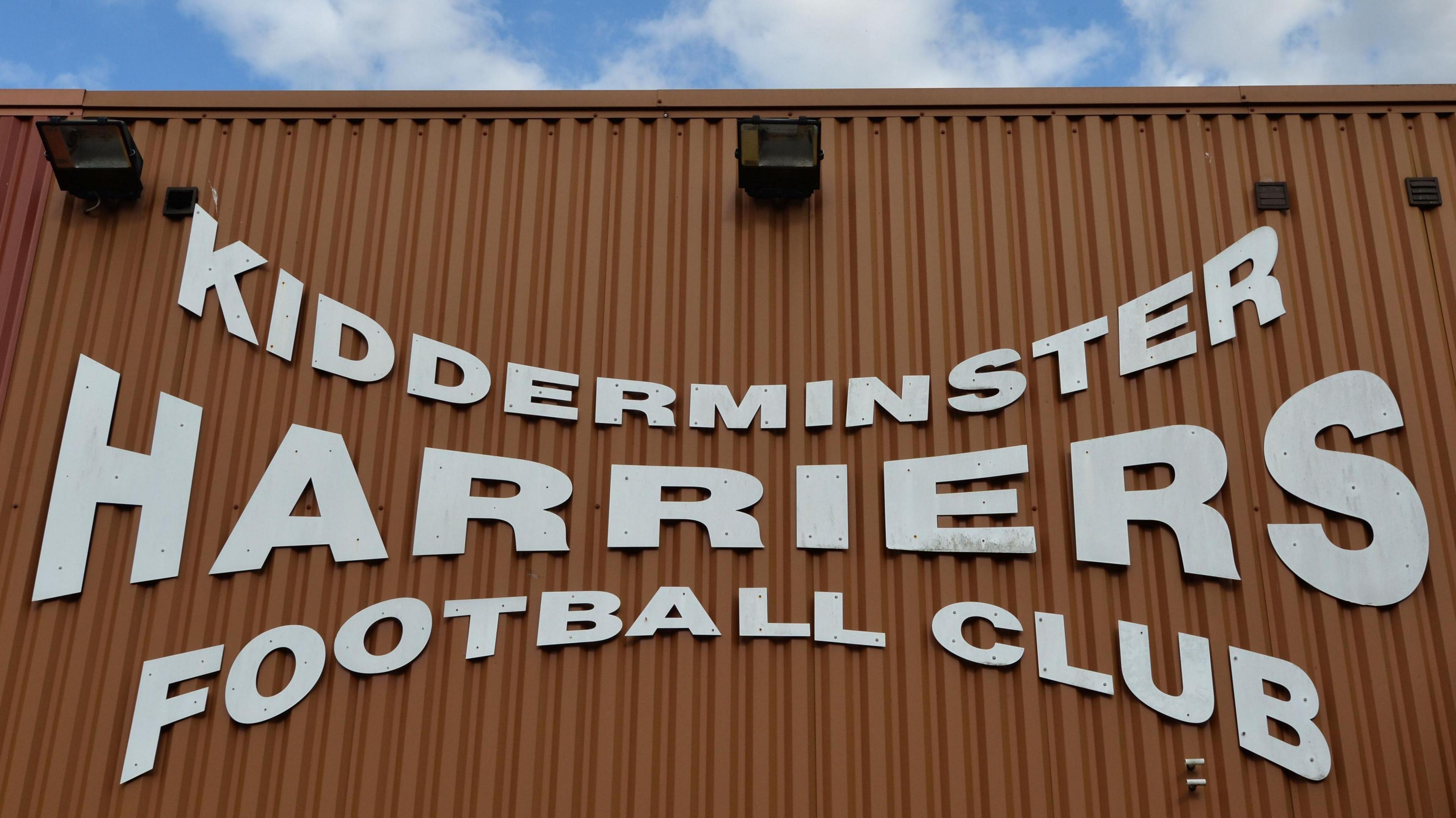 A sign on the exterior of Aggborough Stadium reads 'Kidderminster Harriers Football Club' in white font