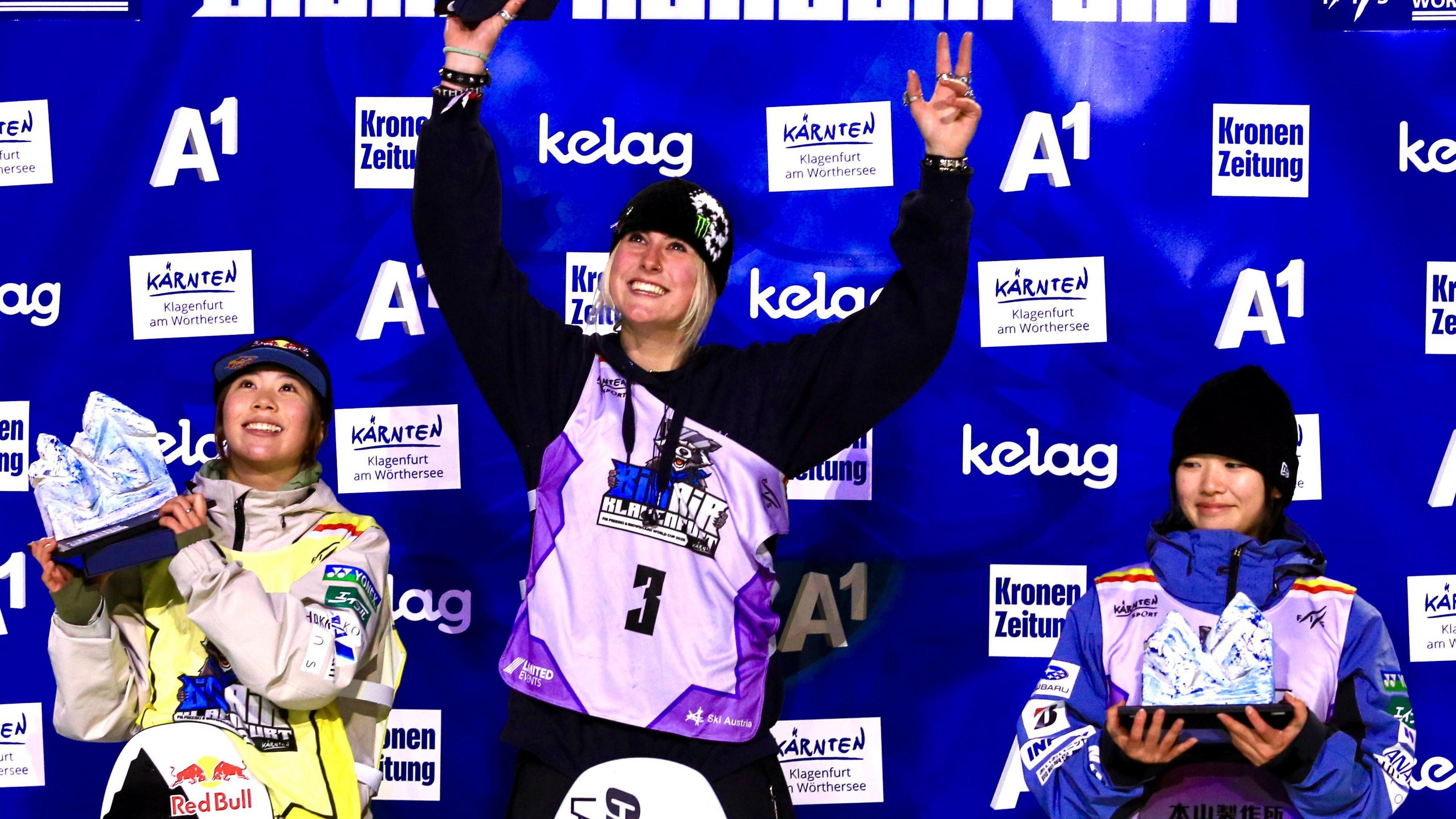 Mia Brookes lifts her trophy on the podium after winning the big air World Cup event in Klagenfurt