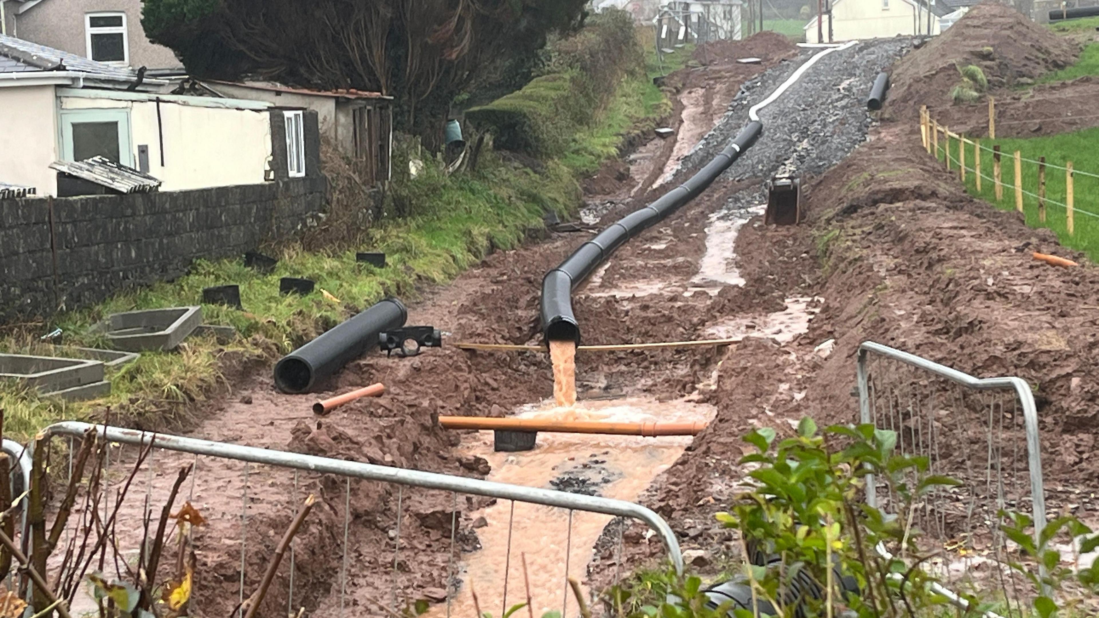 Mae dŵr wedi bod yn cael ei bwmpio o'r safle, ond dydy hynny ddim yn ddatrysiad meddai pentrefwyr