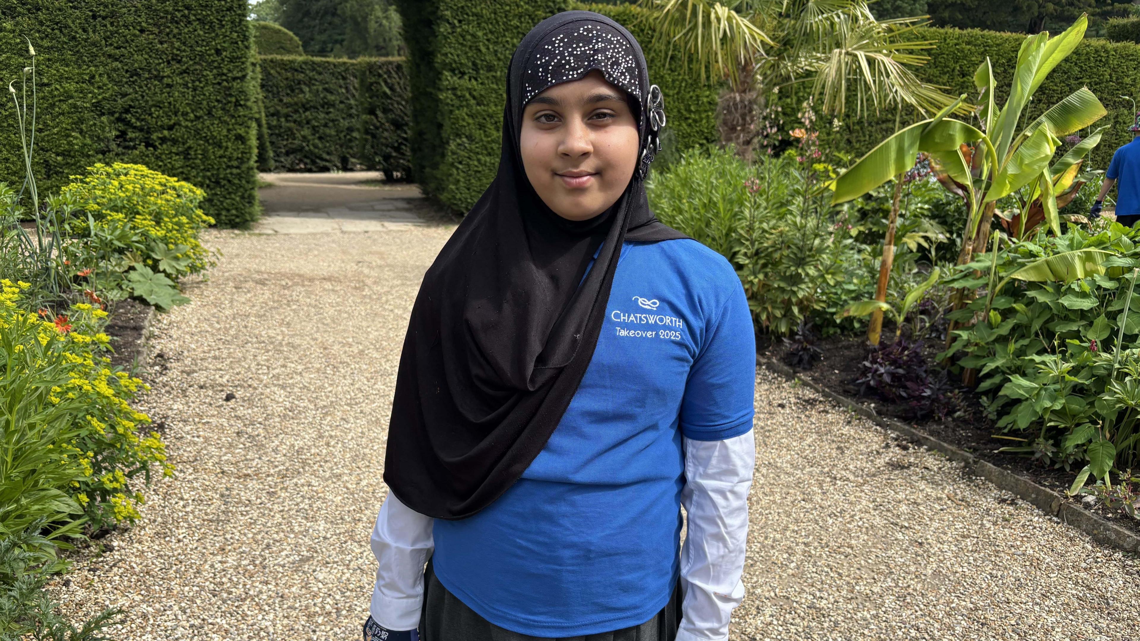 A 10-year-old girl dressed in blue school uniform with a black hijab.