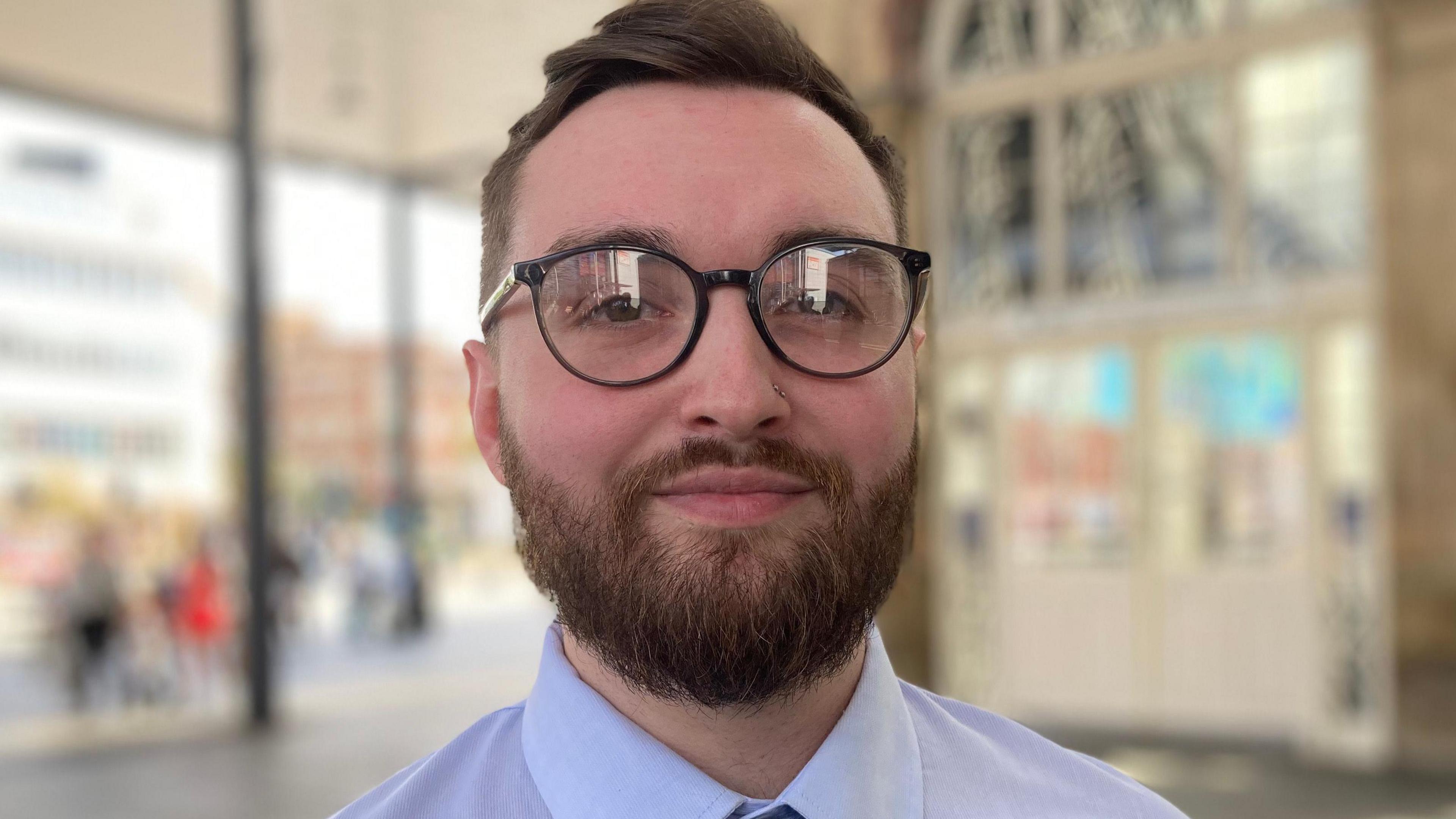 Matthew Cooper wearing round black-framed spectacles on his face and a light-blue shirt