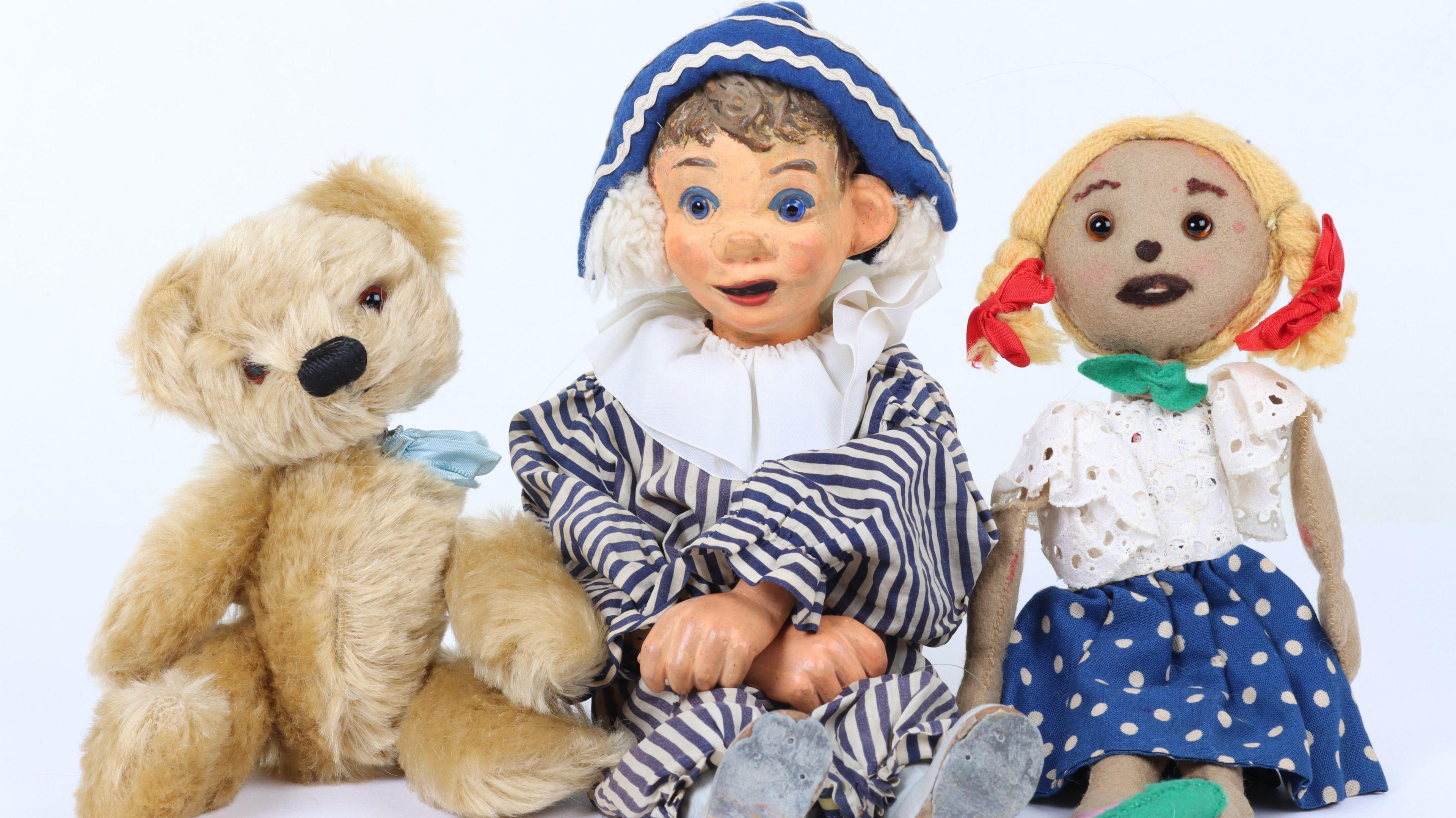 Puppets of Andy Pandy, Teddy and Looby Lou sit side by side against a white wall.