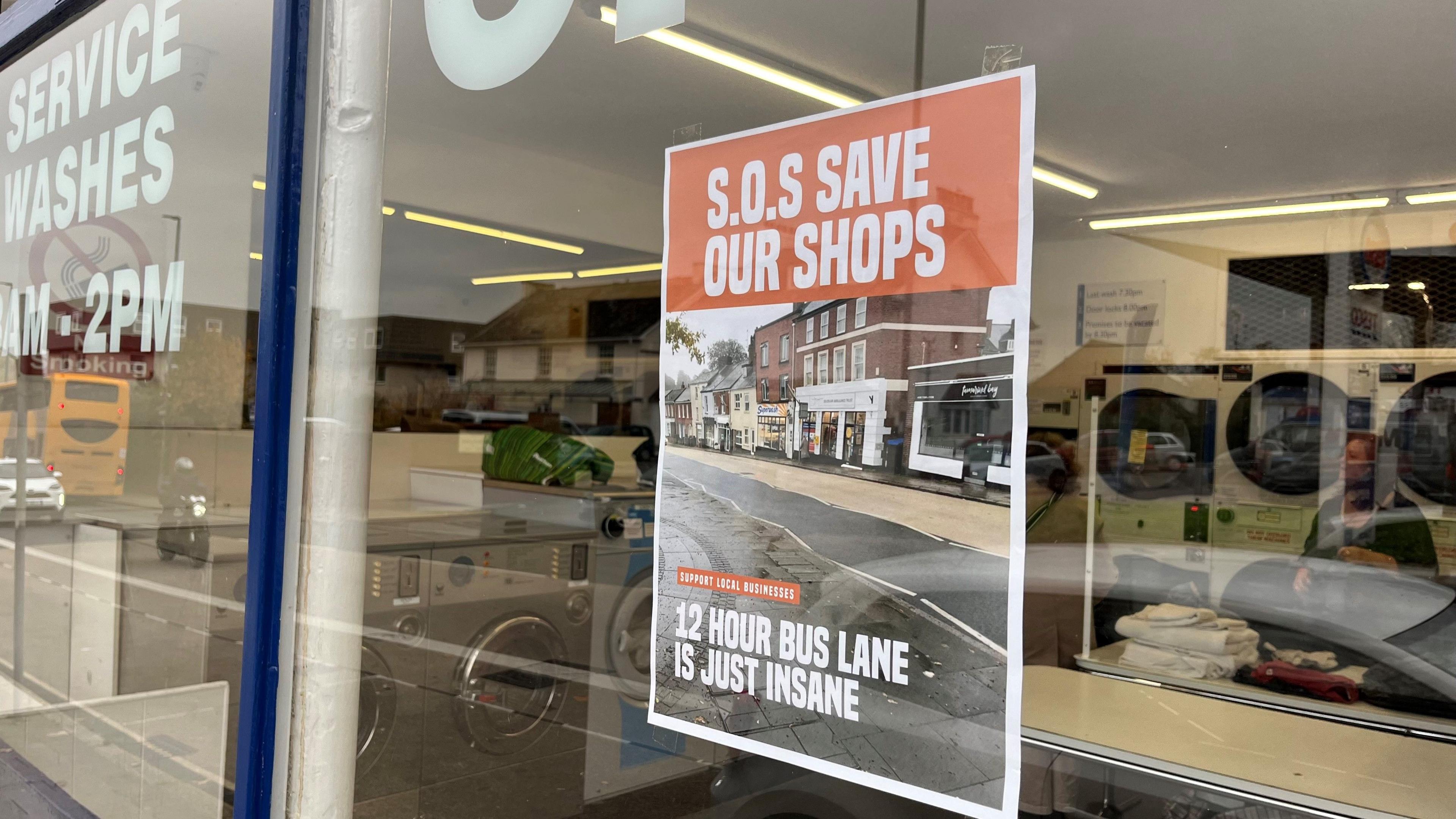 A sign opposing the 12-hour bus lane plans in the laundrette on Fore Street, saying "SOS - save our shops"