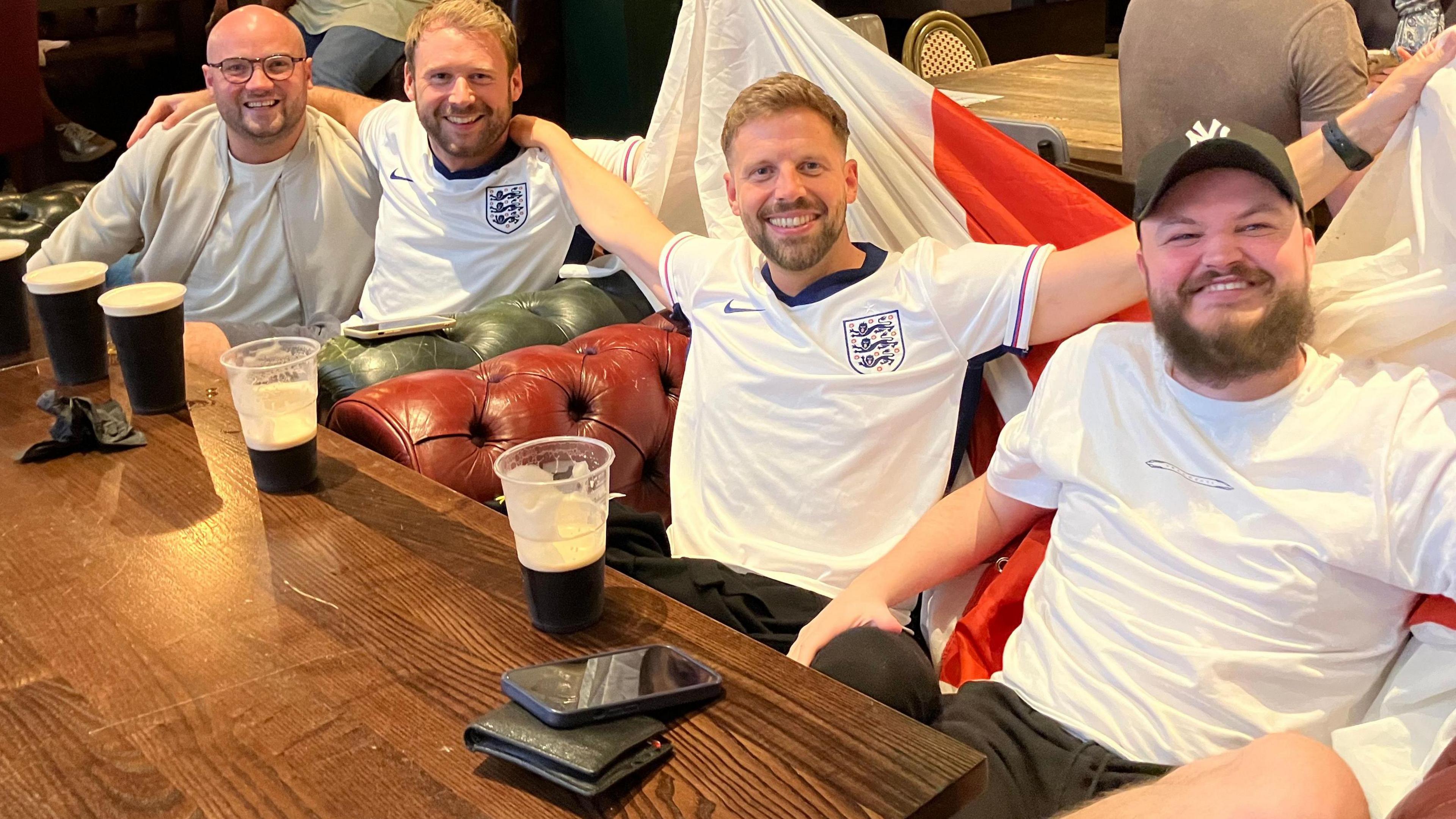 Group of men wearing England shirts on chairs in a pub