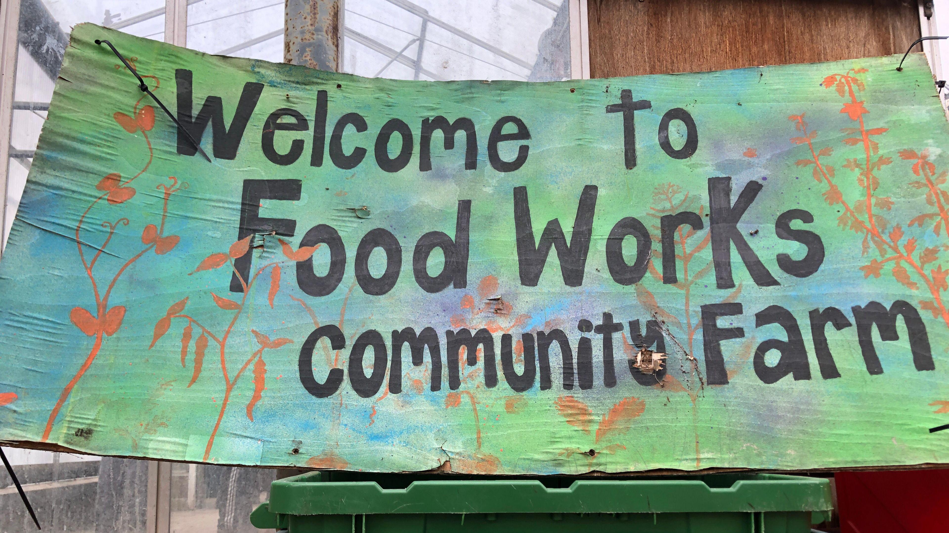 A colourful sign says 'Welcome to Food Works community farm'