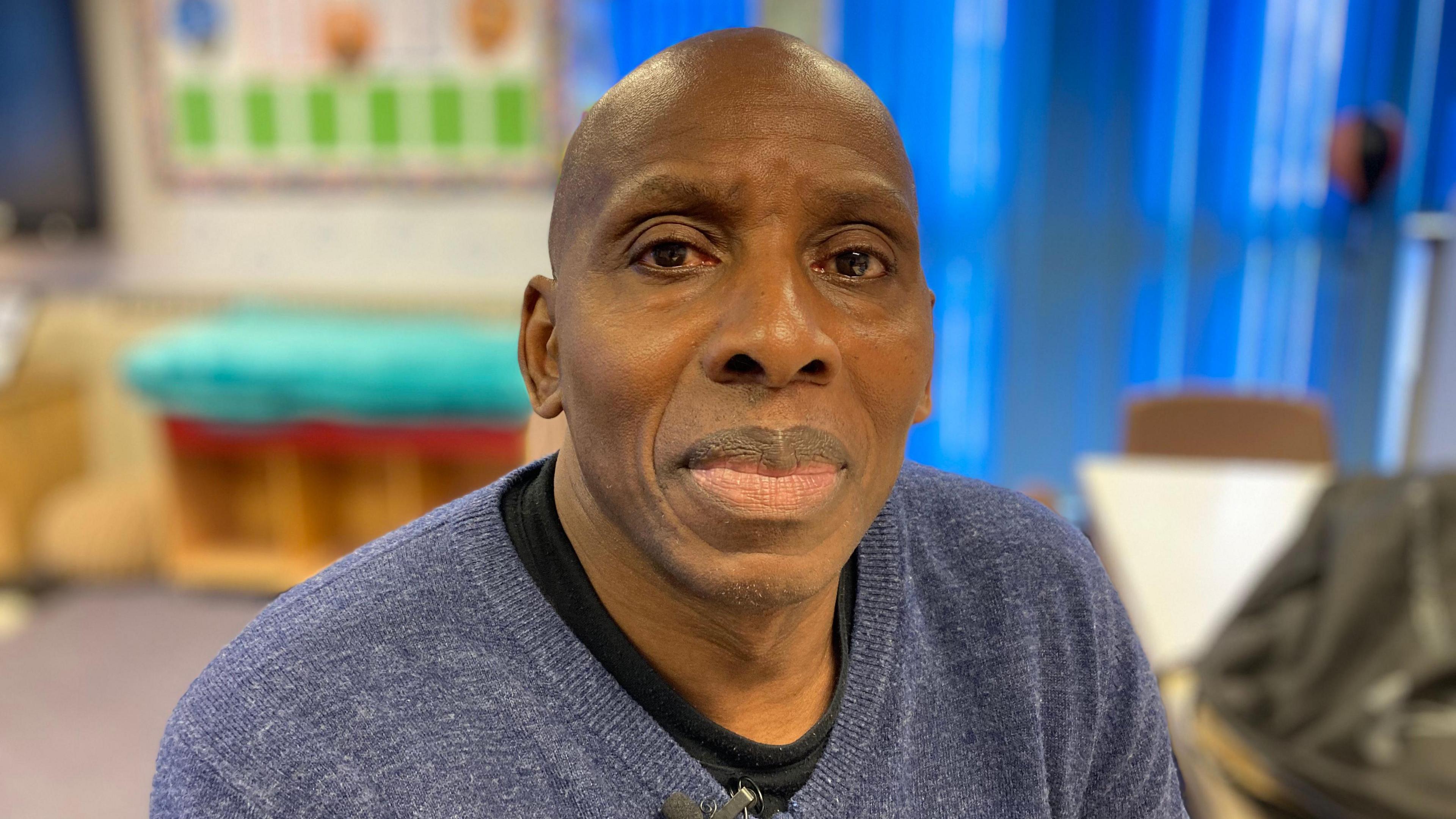 A man in a blue jumper sat in a community centre