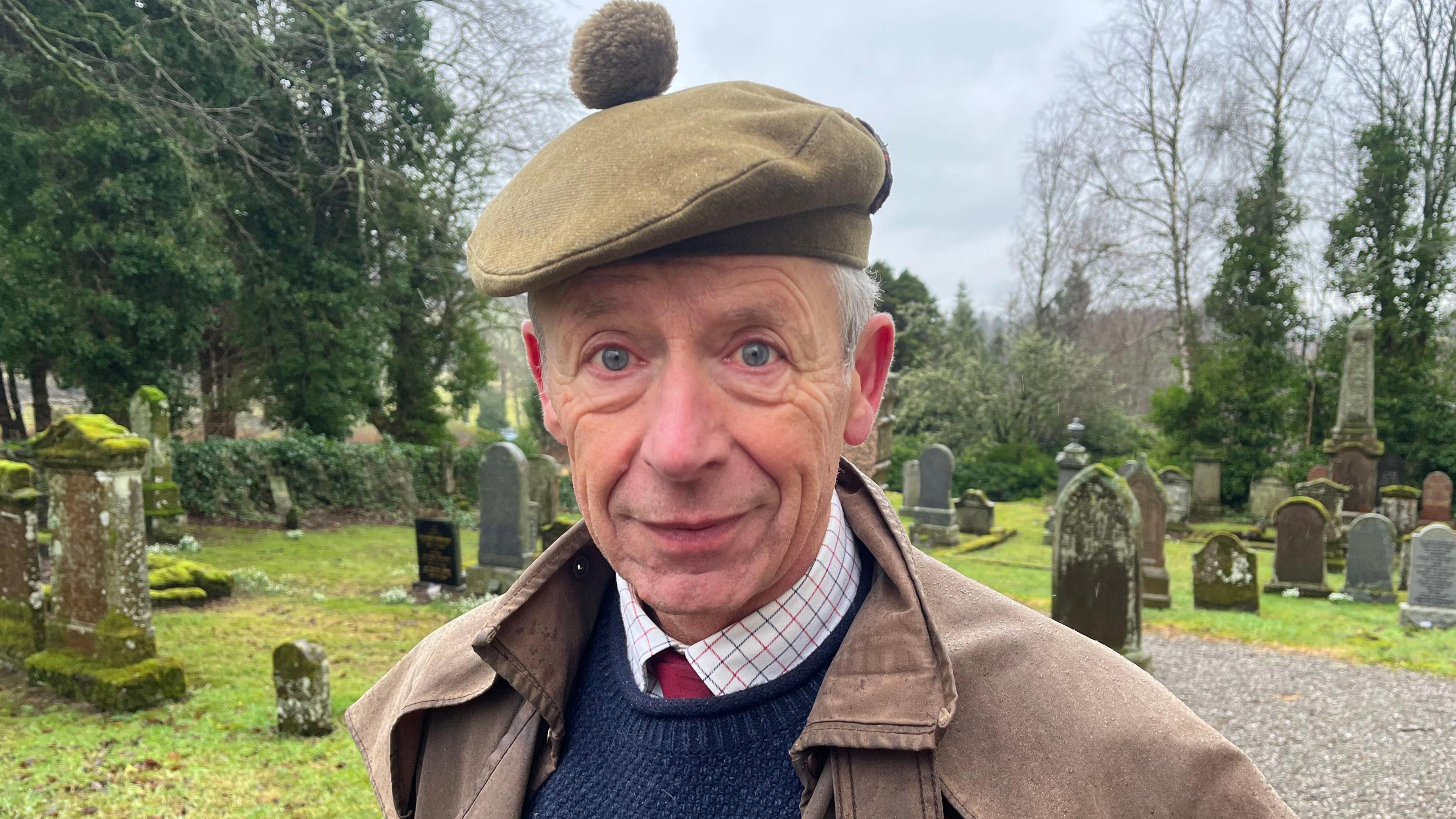 An t-eòlaiche eachdraidh Peadar Dòmhnallach OBE na sheasamh ann an cladh