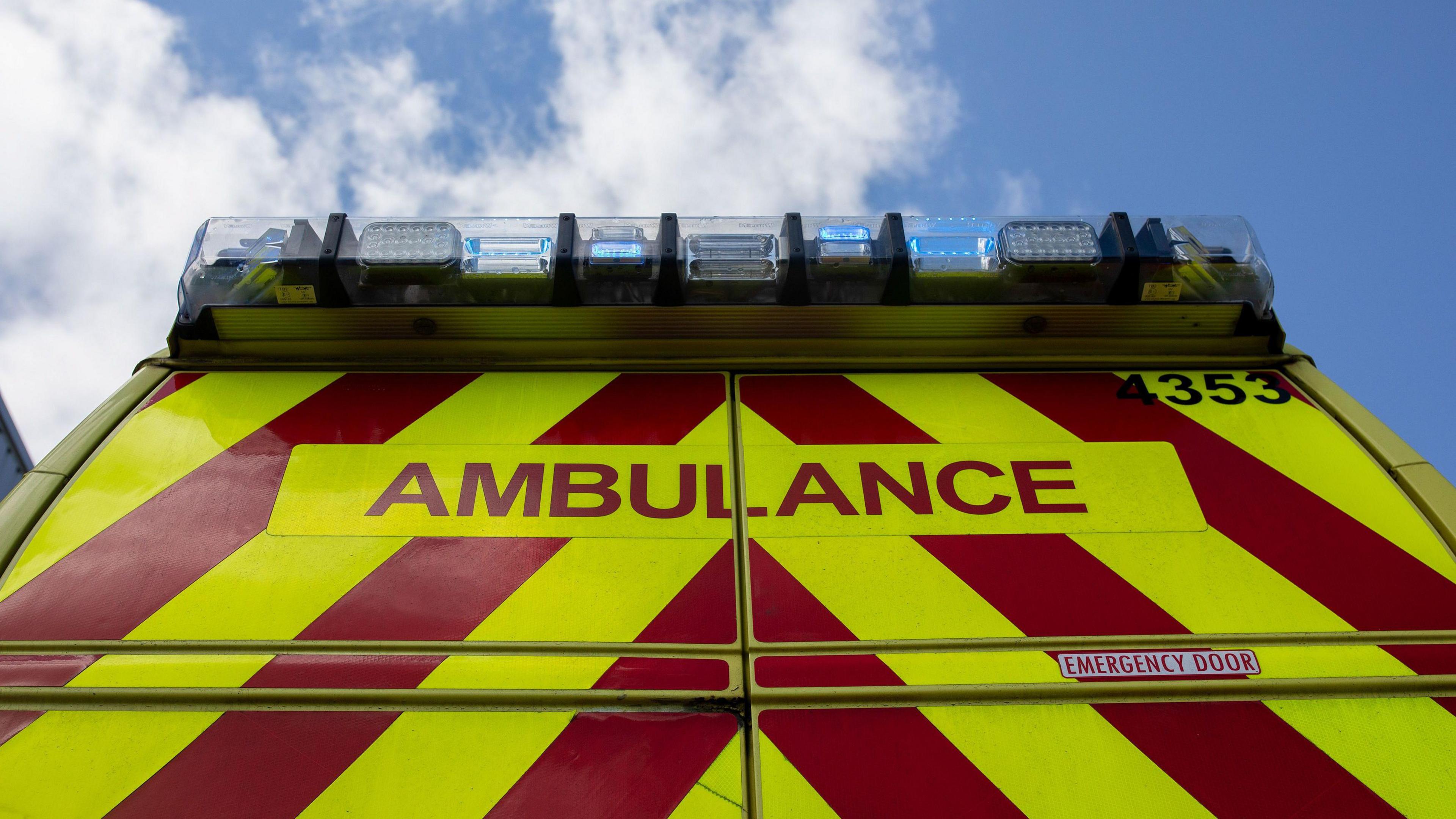 The rear of an ambulance against a blue sky with clouds 